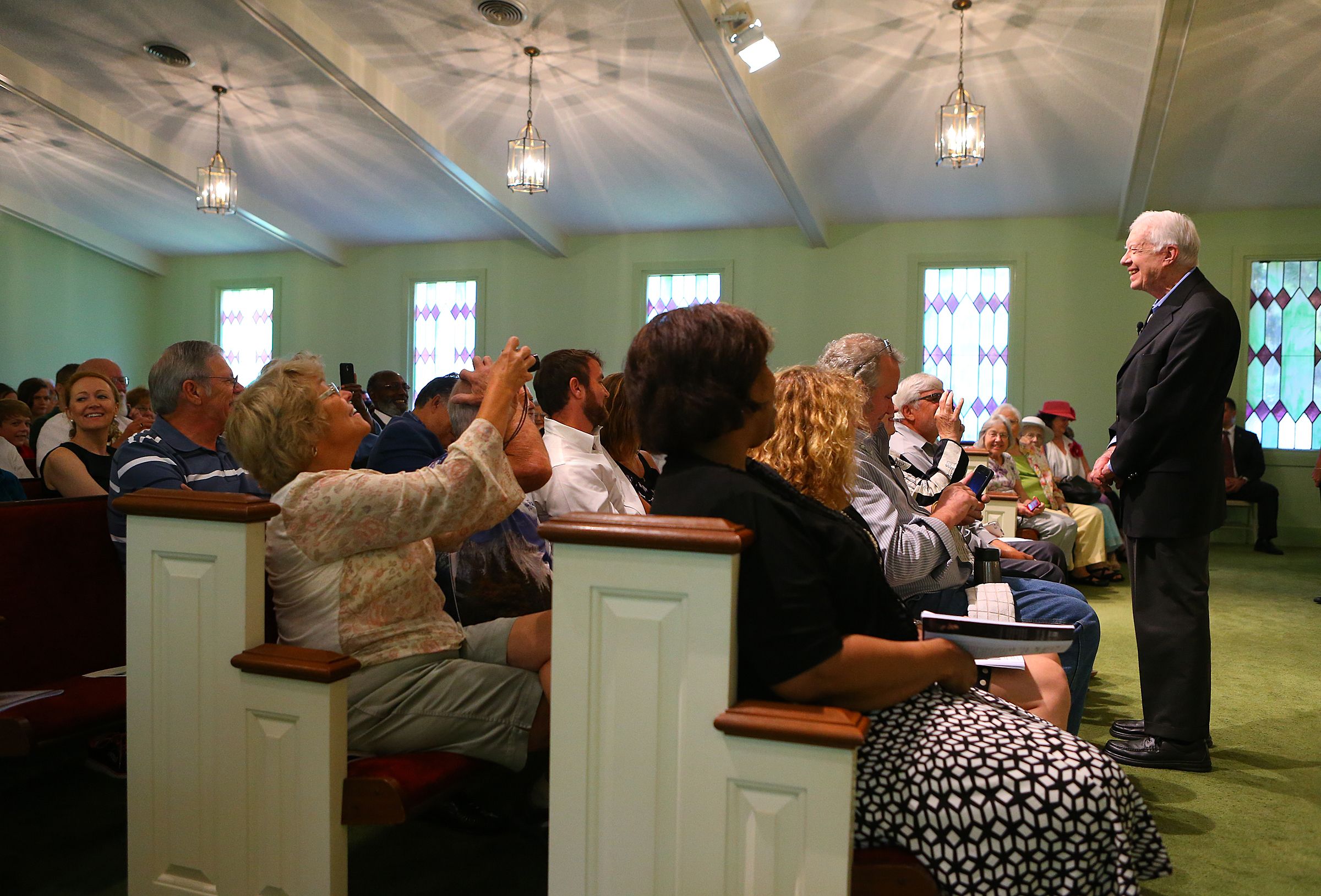 Jimmy Carter, now in his 90s, begins a Sunday school lesson at Maranatha Baptist Church in his hometown of Plains in 2014. Members of the congregation snap photos