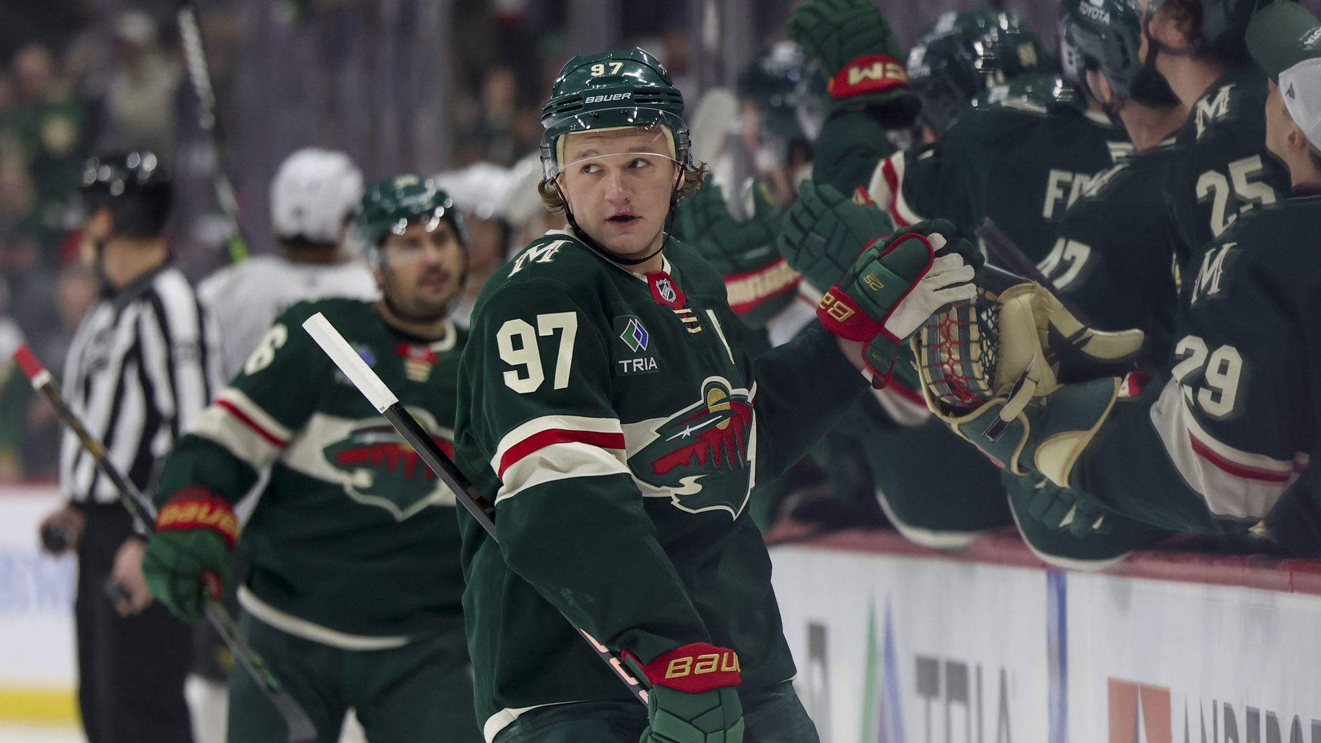 A hockey player gives fist bumps along the bench after scoring a goal