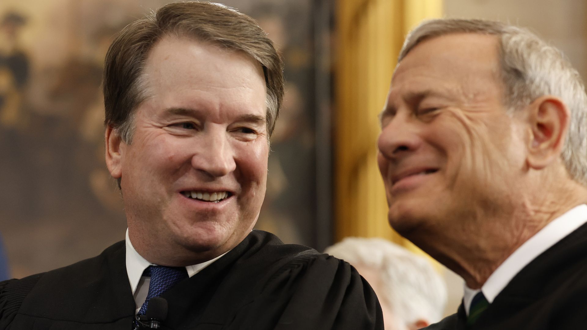 Brett Kavanaugh and John Roberts laugh as they talk.