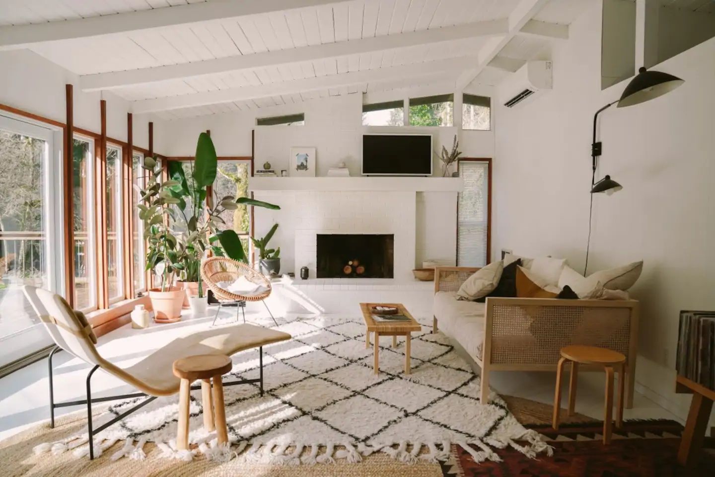 A bright living room filled with mid-century furniture and plants.