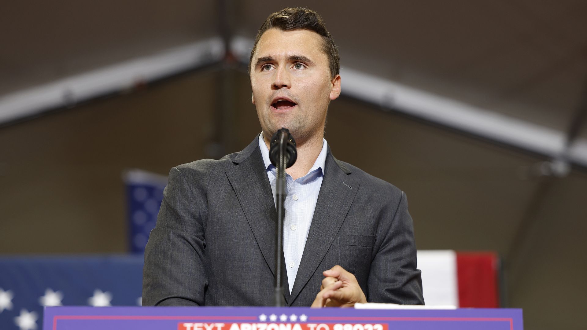 Charlie Kirk at a podium that says "Text Arizona to 88022 TRUMP"
