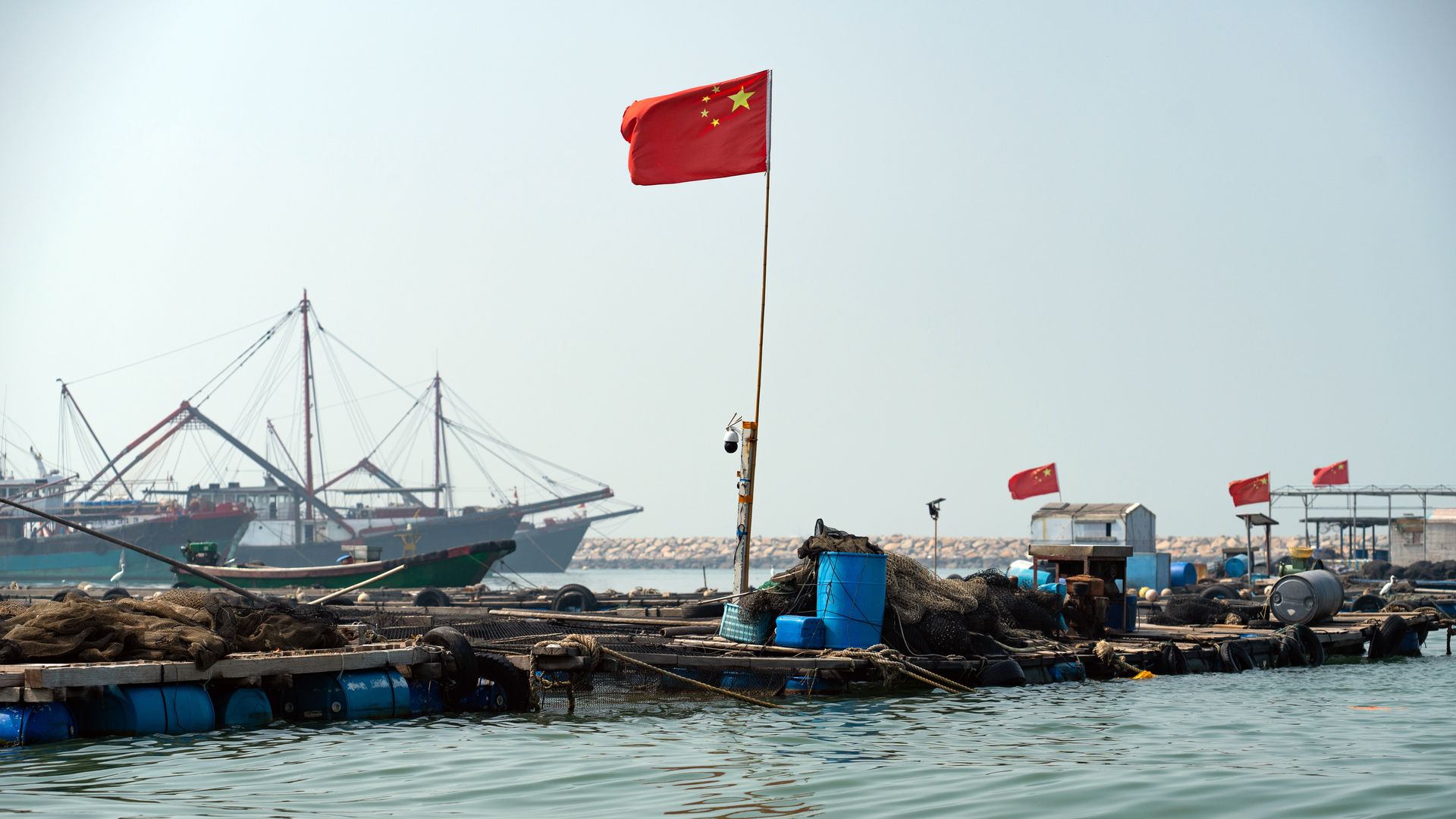 A Chinese flag waving with fishing vessels in the background in the South China Sea