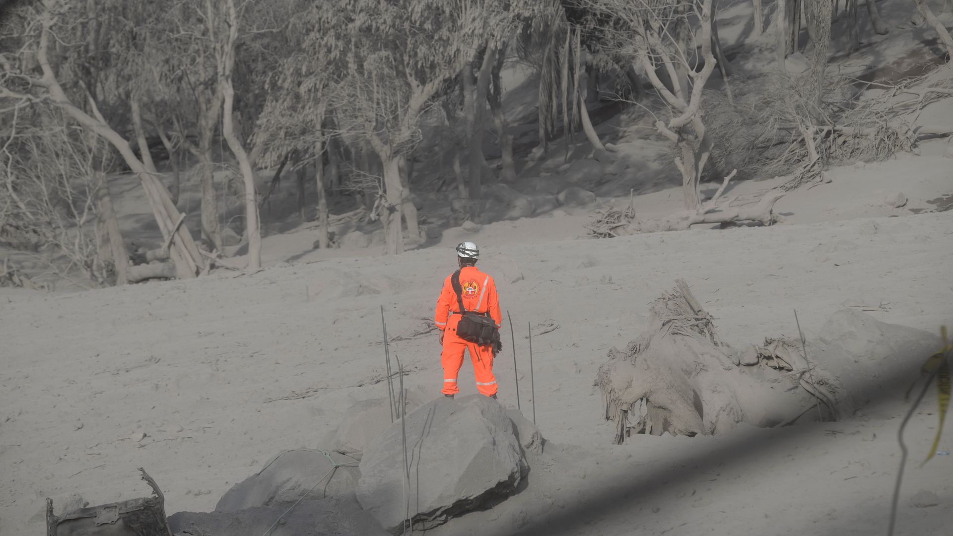 A firefighter standing in an area covered by ash after the eruption of the volcano.