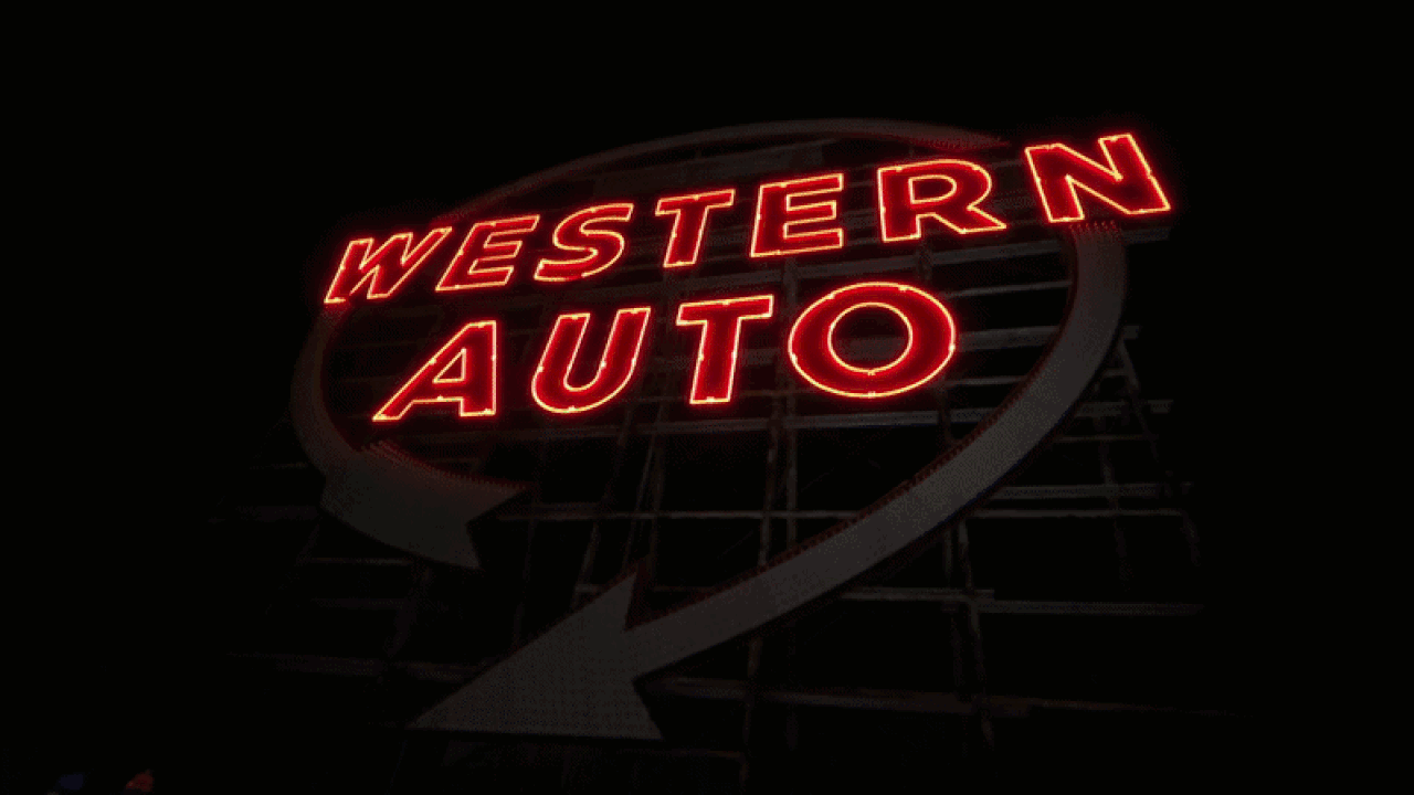 Night scene of a red neon sign reading WESTERN AUTO, mounted on a circular frame, glowing against a dark background.