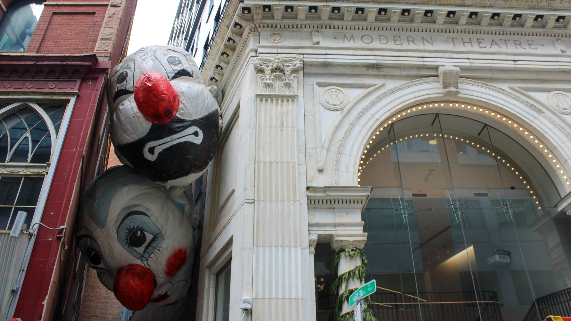 Two massive, inflatable clown heads hang in an alley between two buildings in downtown Boston. It's an art installation called "Endgame" by artist Max Streicher
