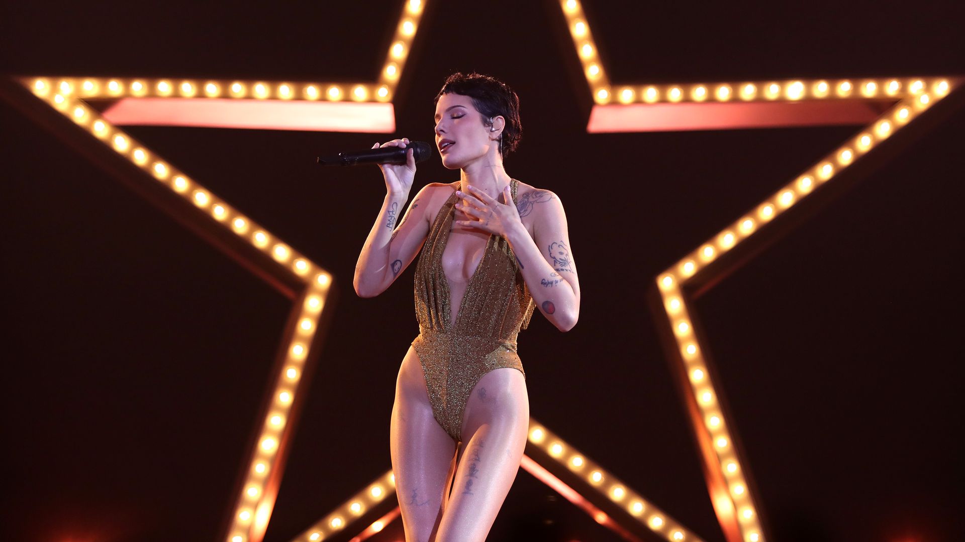 Halsey performs on stage in front of a lit up star. 