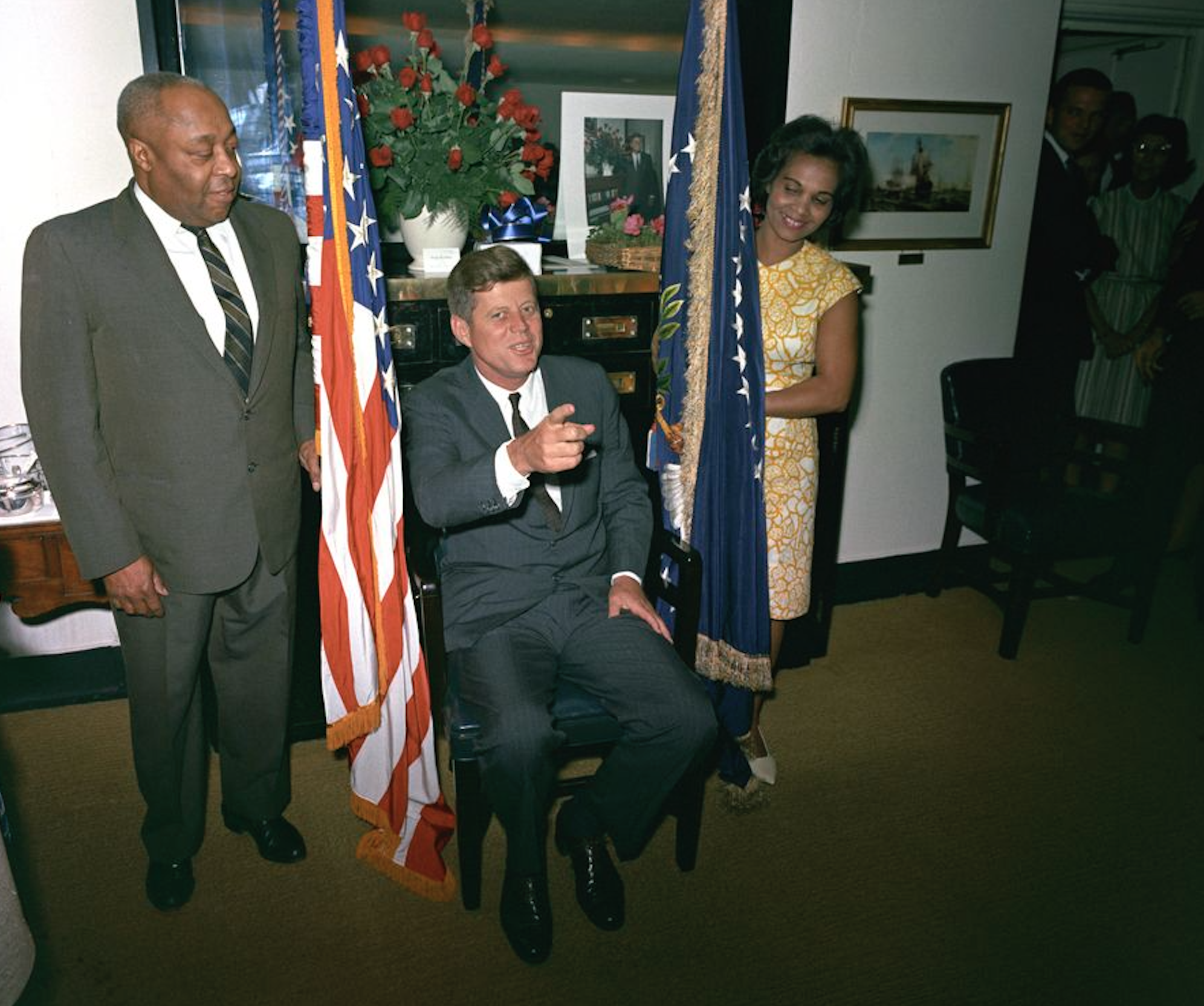 President John F. Kennedy (center) attends a surprise party thrown by members of the White House staff in honor of his 46th birthday. President Kennedy’s valet, George E. Thomas, stands at left; First Lady Jacqueline Kennedy's personal assistant, Providencia "Provi" Paredes, stands at right. 