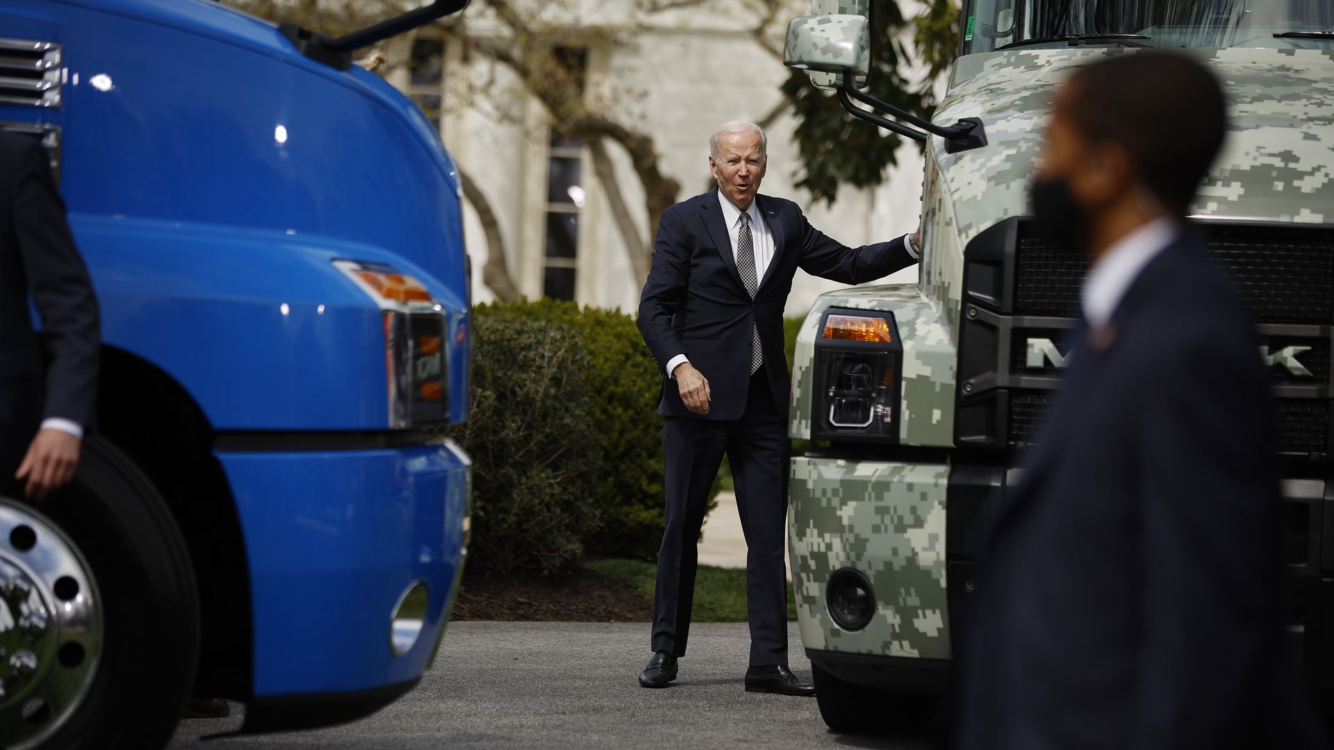 President Biden is seen standing between two trucks during a White House event on Monday.