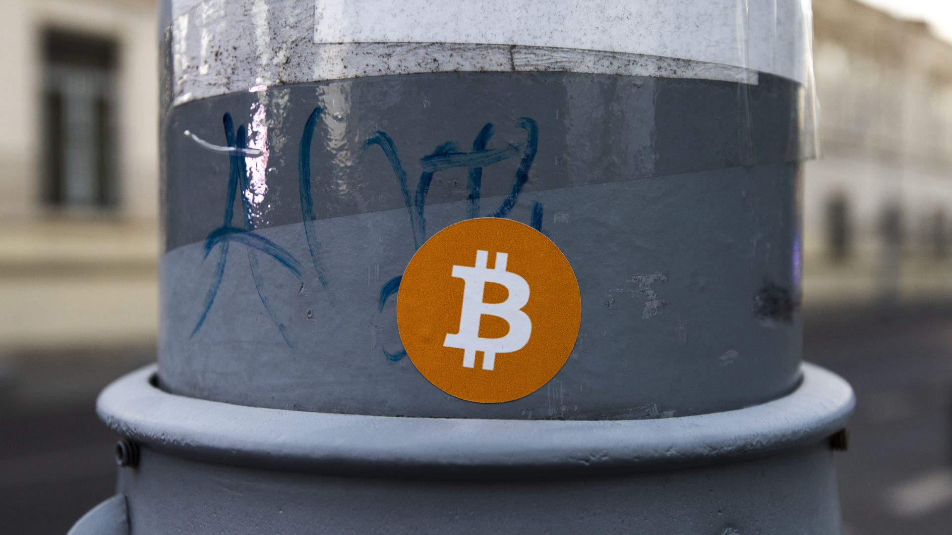 A sticker with the Bitcoin logo on it, on a lamp post.
