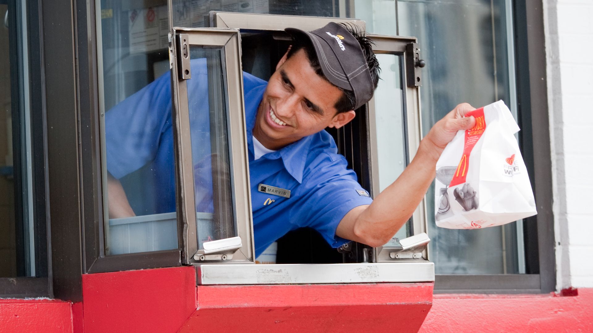 Image of a McDonald's worker leaning out a drive thru window.