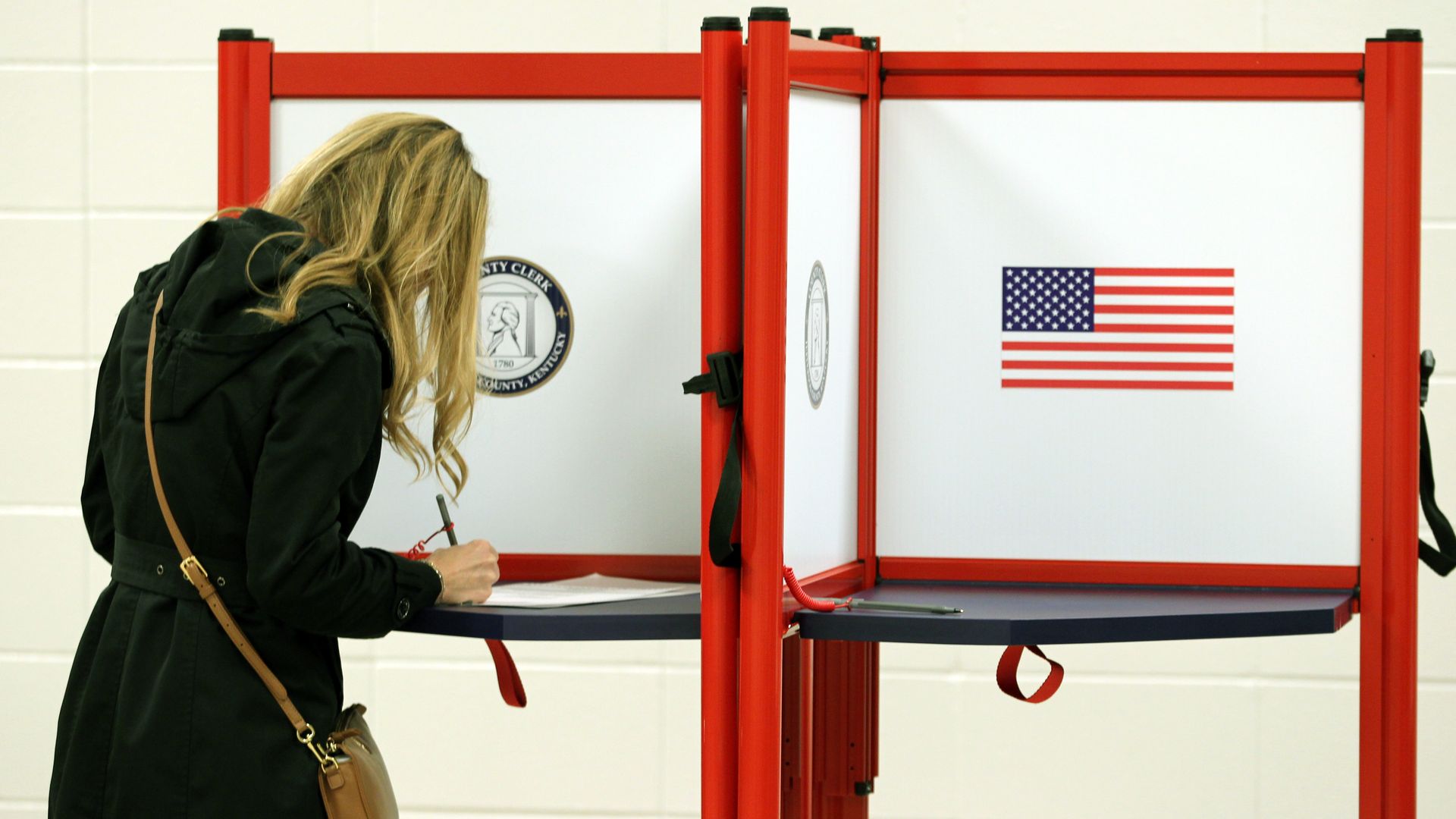 In this image, a woman leans over a voting booth