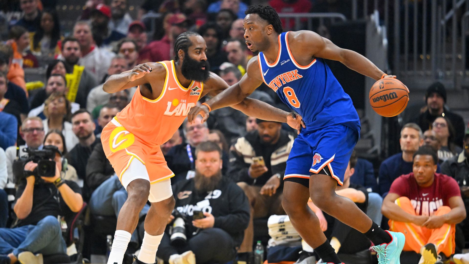 Bearded player in cream orange jersey defense muscular black player in Blue new york jersey on basketball court. 