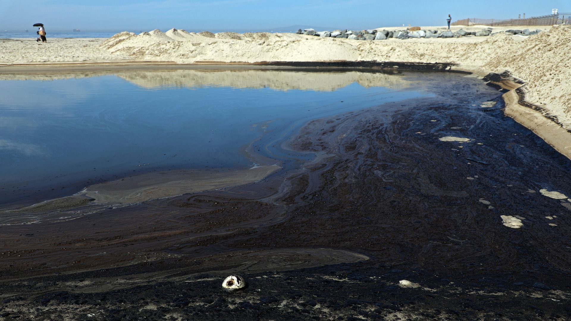 Dark, sticky oil settles into a pool of water on Huntington Beach, California