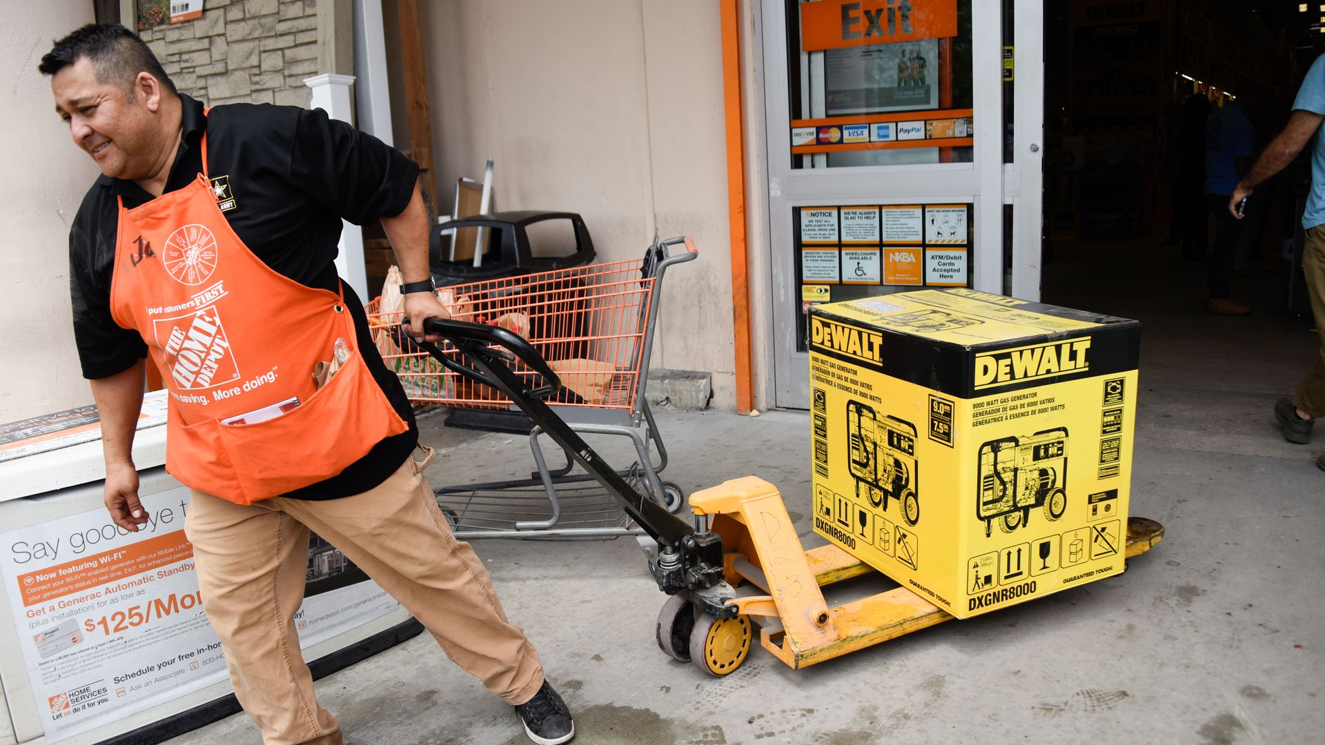 A Home Depot employee pulls a generator on a cart