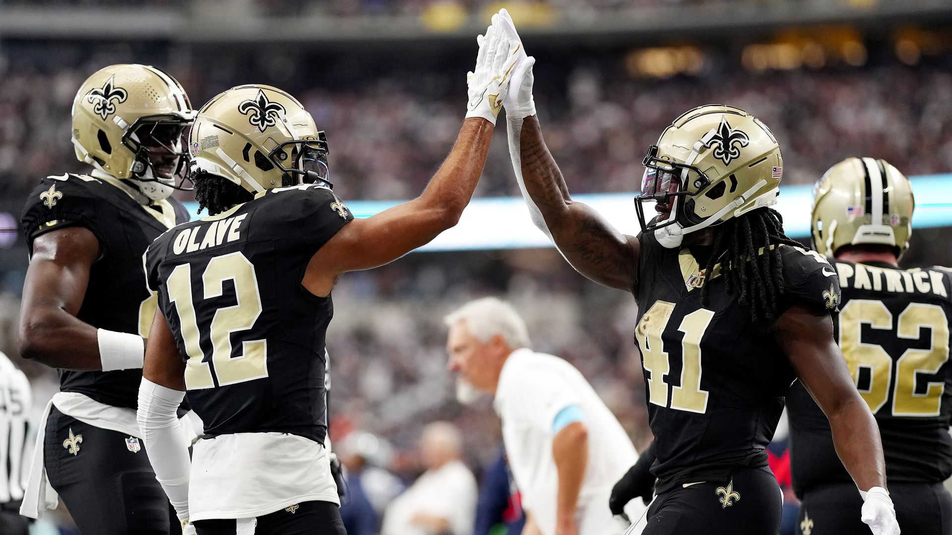Two Saints players high-five during a game.