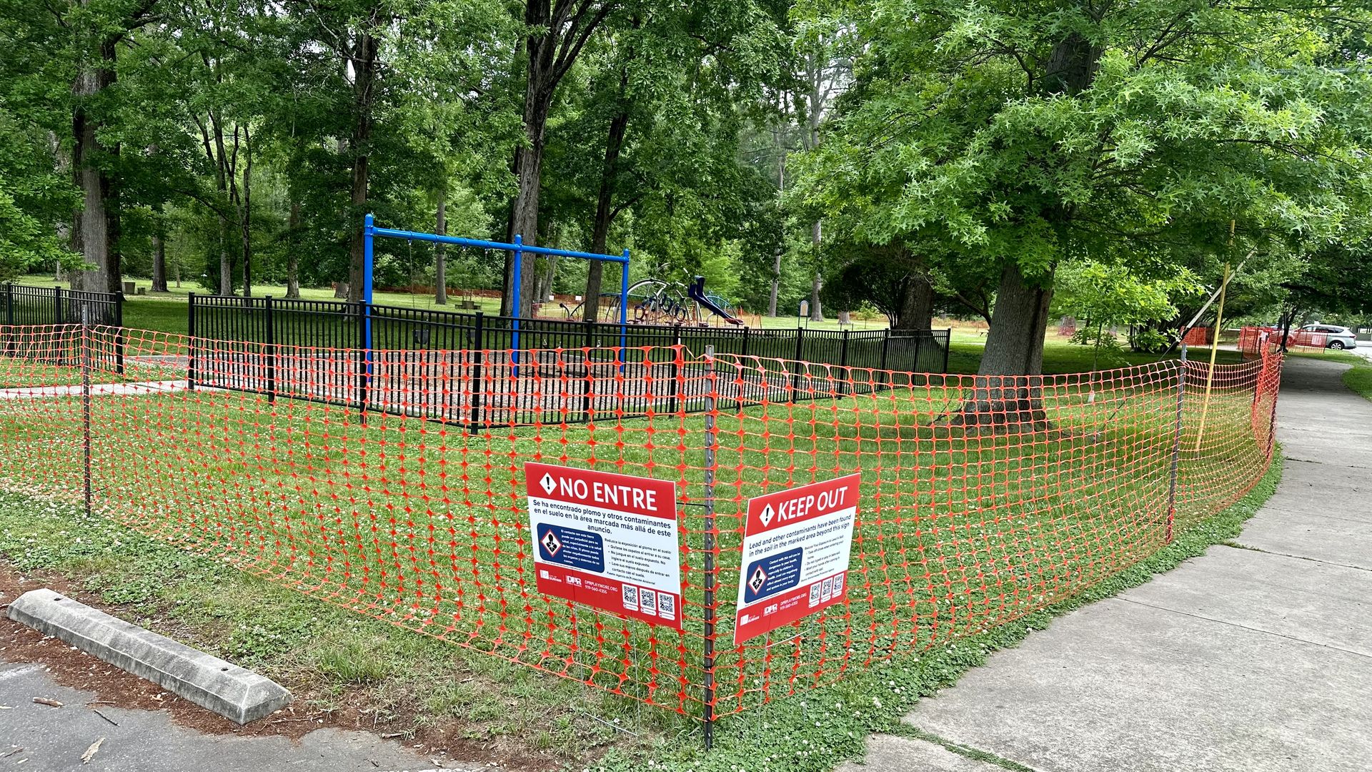 A fenced off section of a park with signage saying to keep out