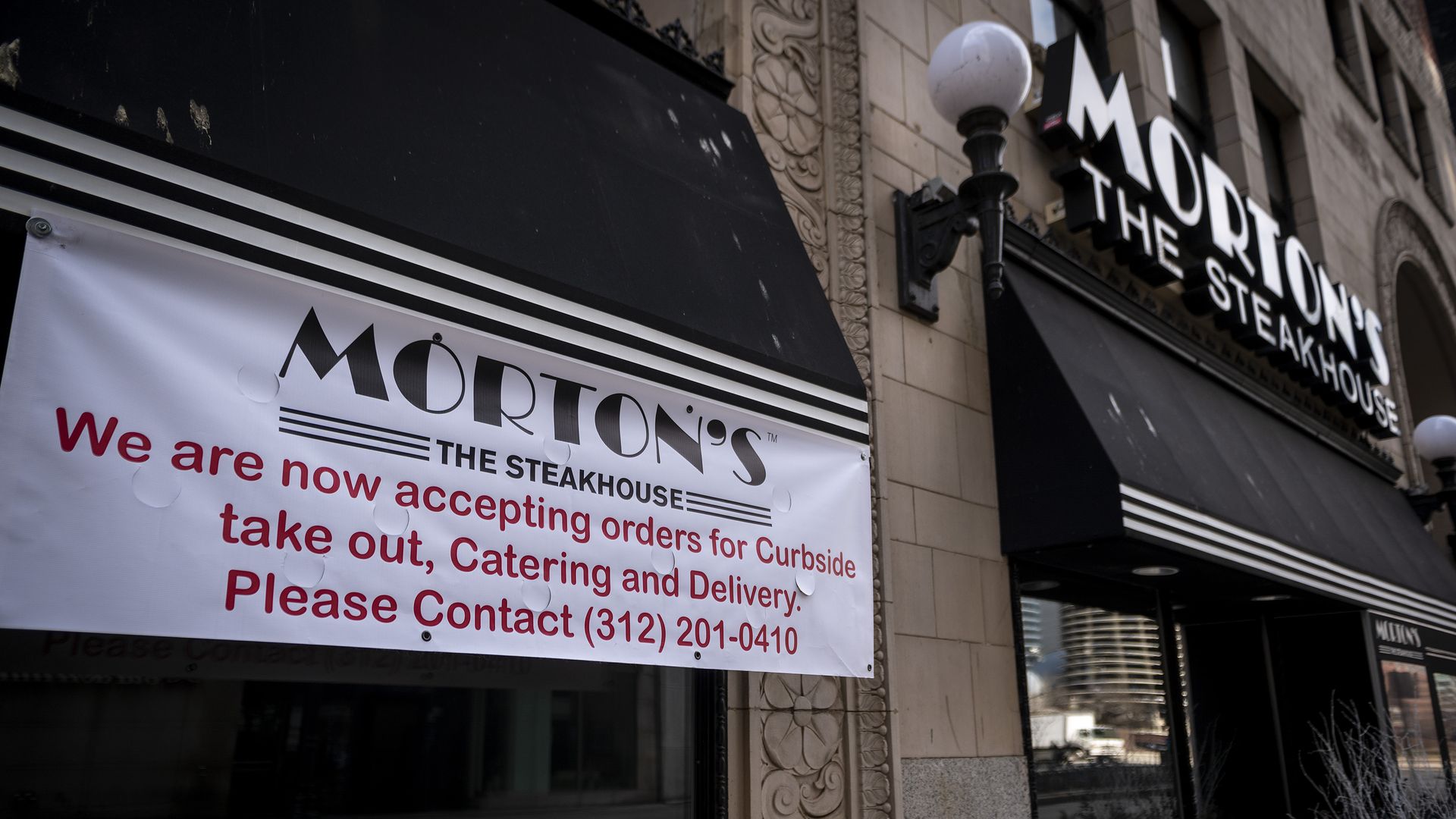 Photo of a sign on a restaurant promoting carryout and curbside delivery. 
