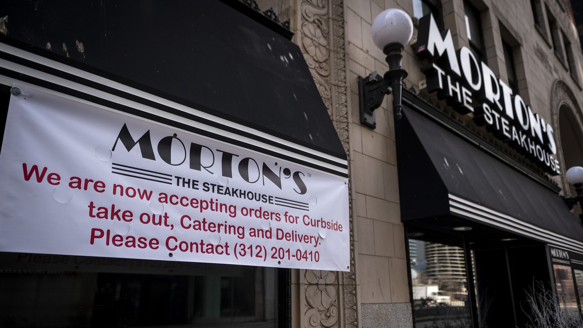 Photo of a sign on a restaurant promoting carryout and curbside delivery.