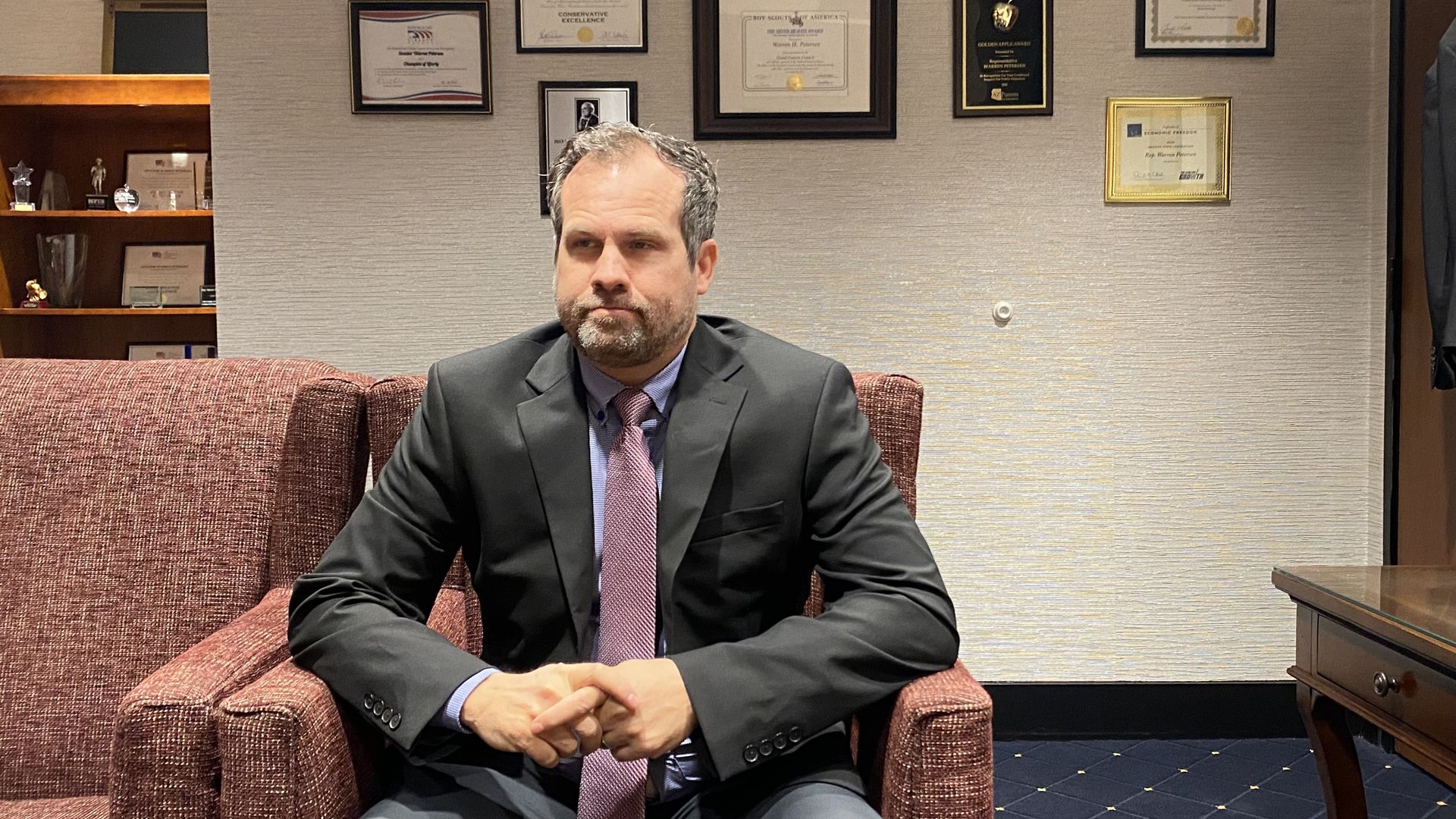 Warren Petersen sits on a chair in his office.