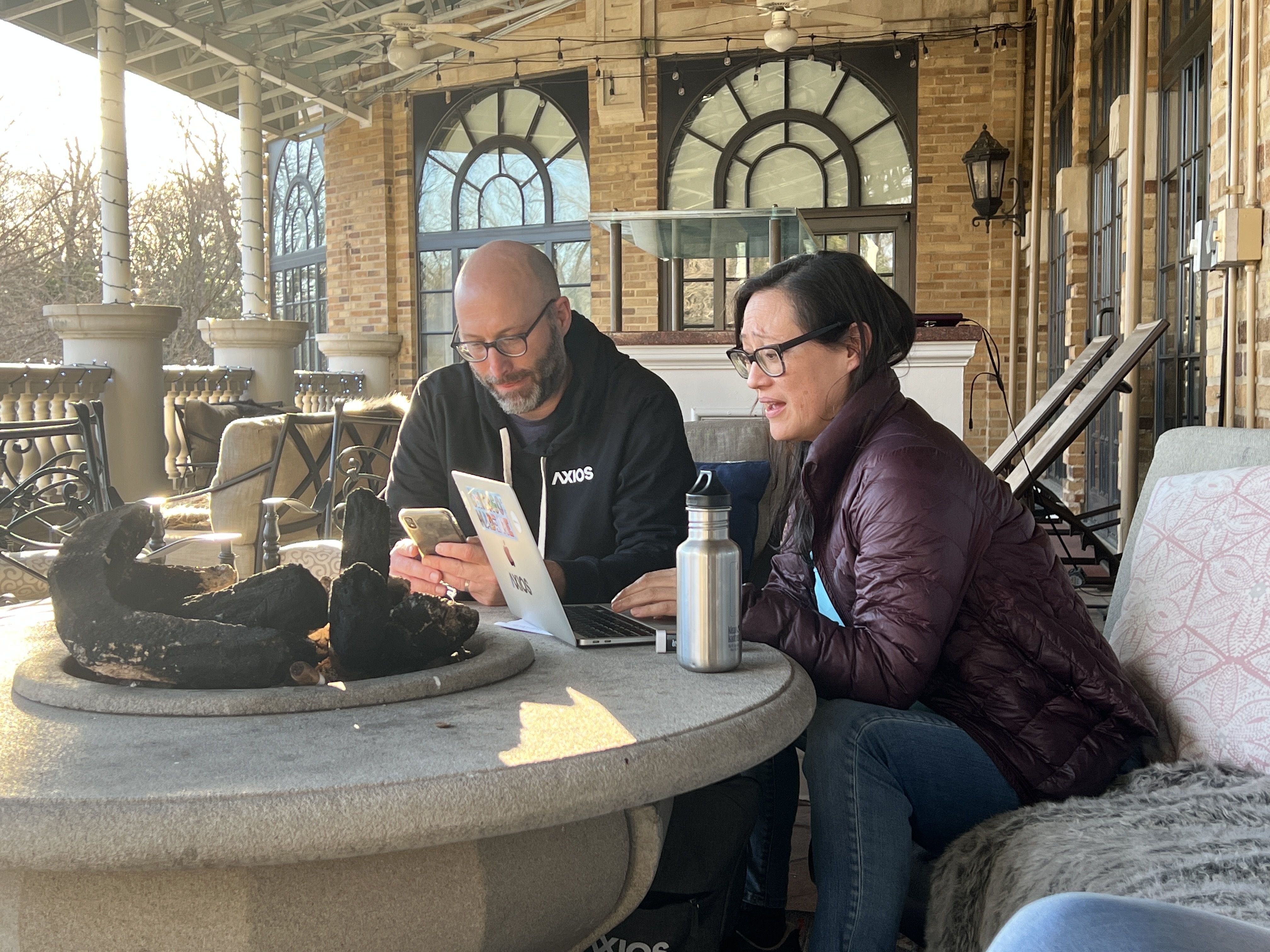 Photo of two people working on a computer while sitting outside
