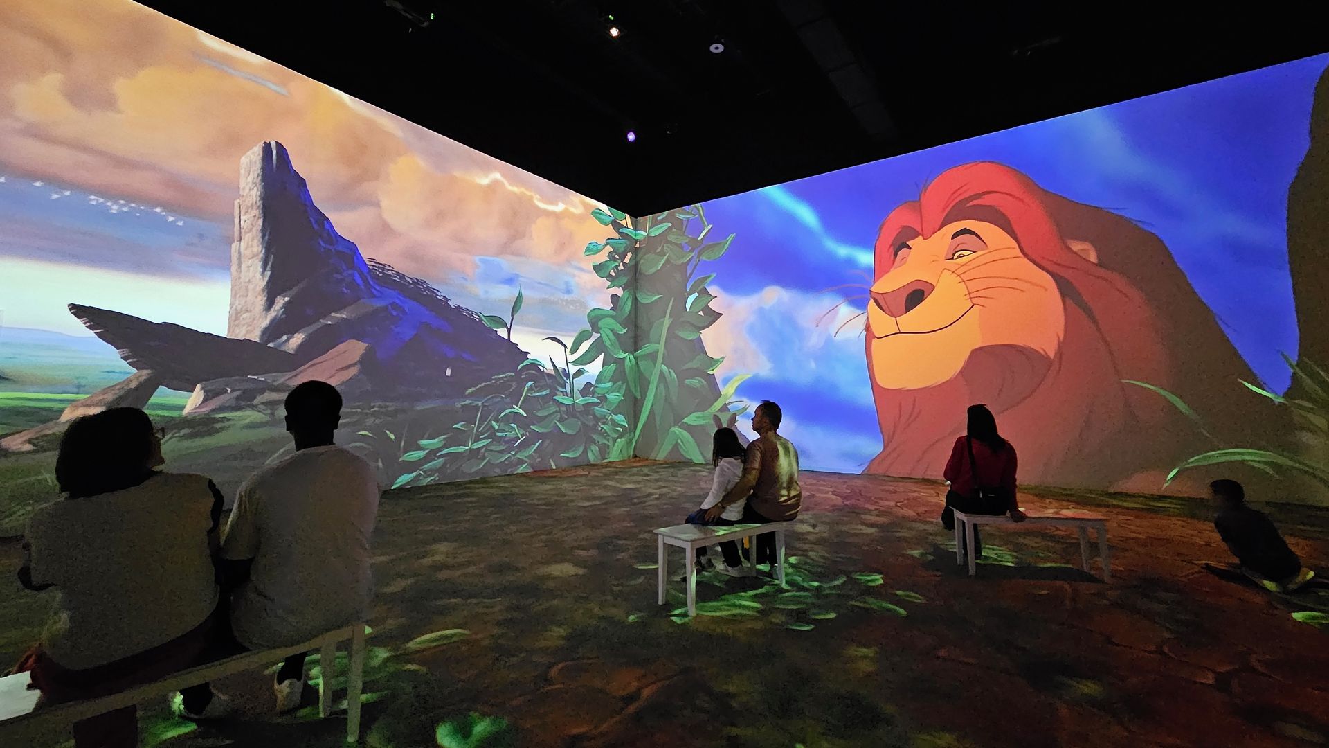 A digital projection of Mufasa and pride rock from "The Lion King" on two walls