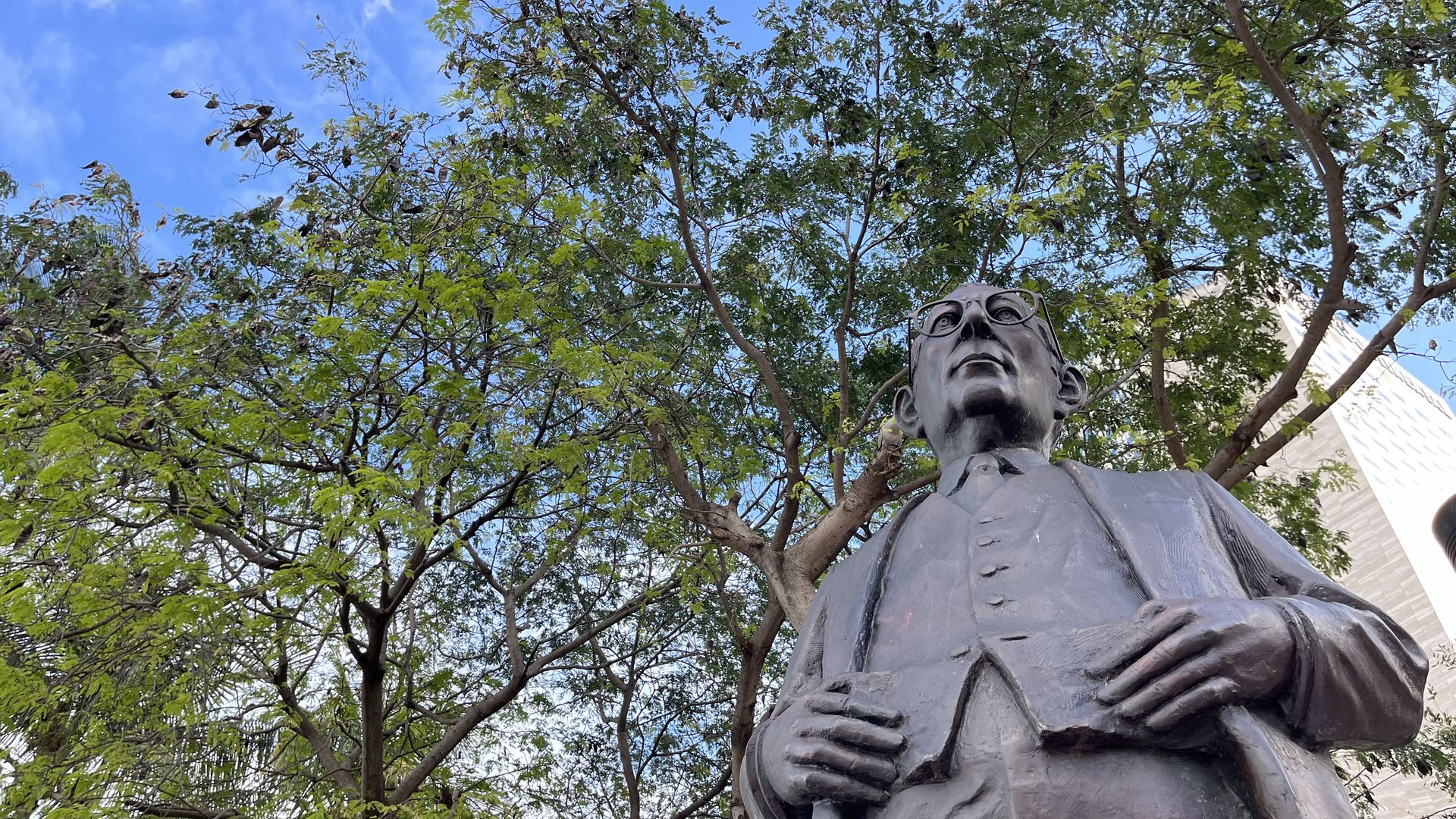 A statue surrounded by trees and tall buildings.