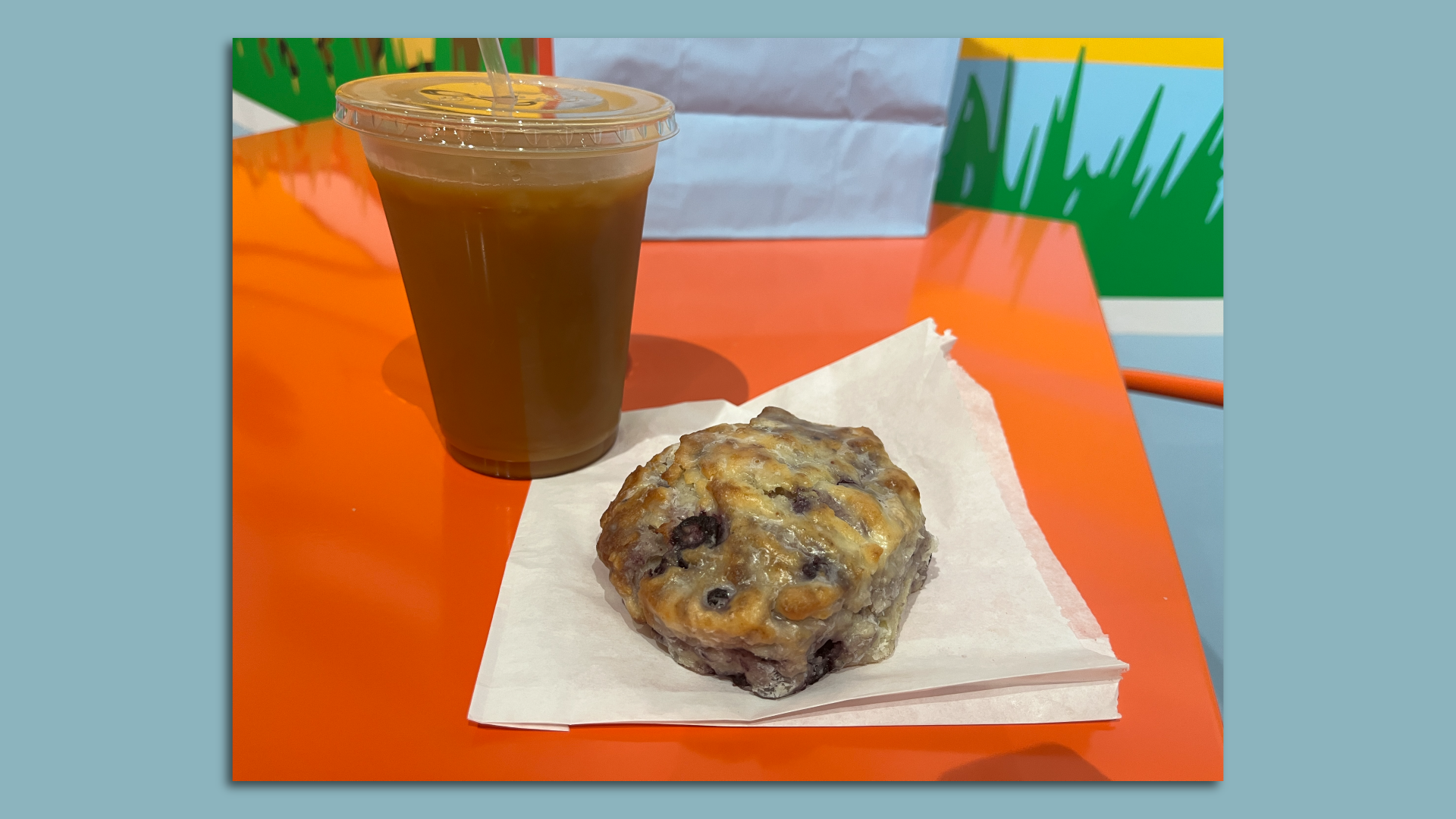 A frosted blueberry biscuit and an iced coffee.