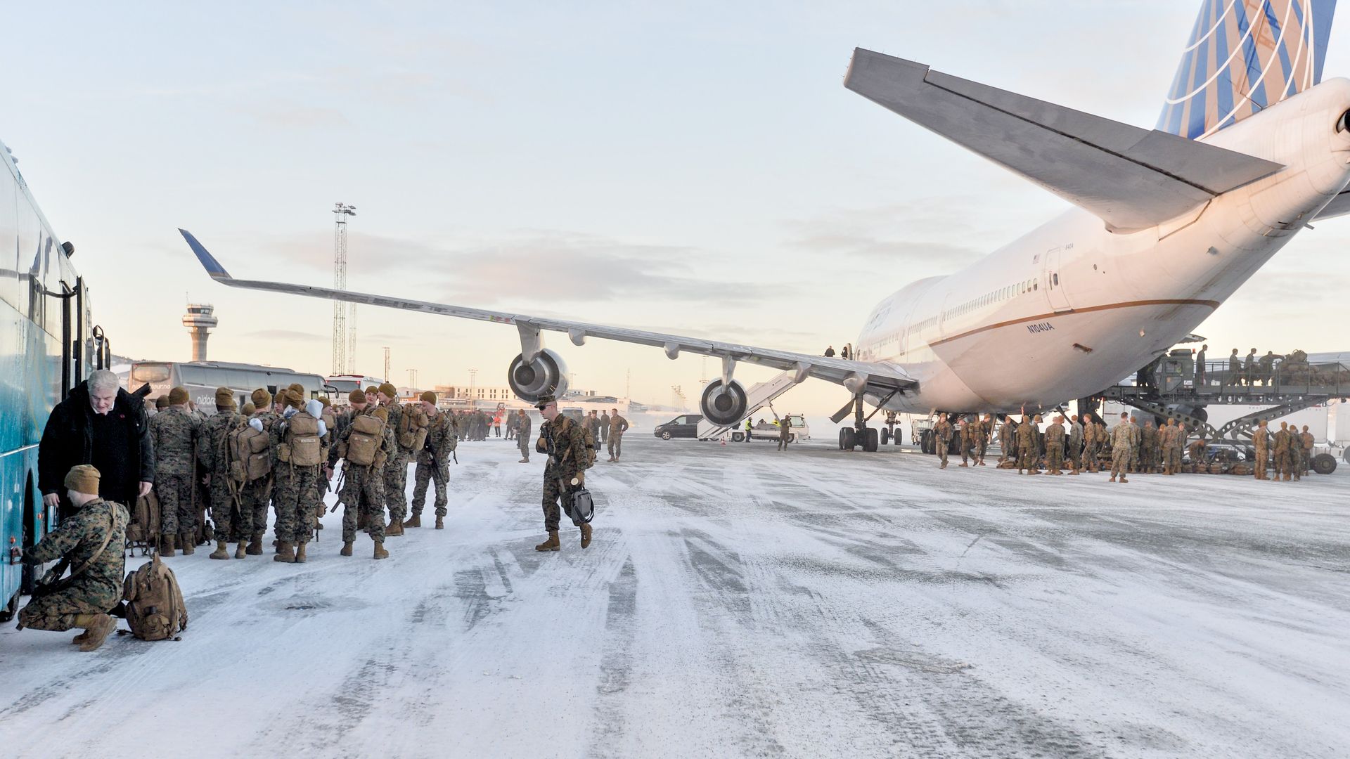 U.S. Marines disembark fro a plane onto a snowy tarmac.