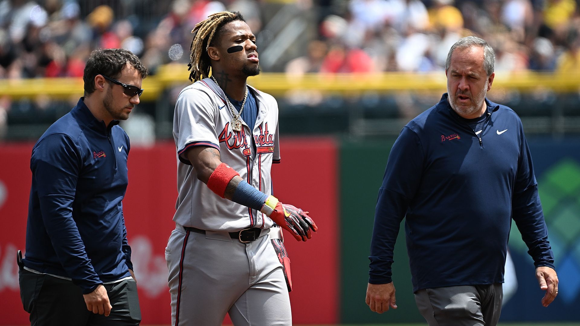 Ronald Acuña Jr. walks off the field with trainers after suffering an injury.