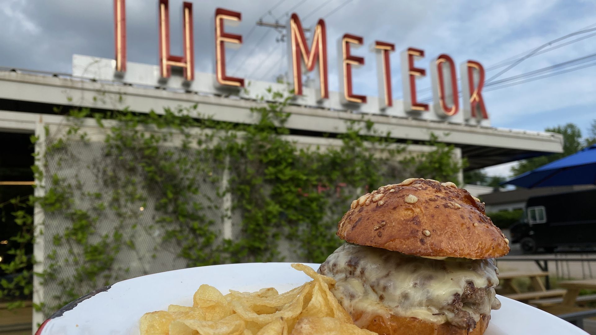 A cheeseburger sits on a plate with potato chips.