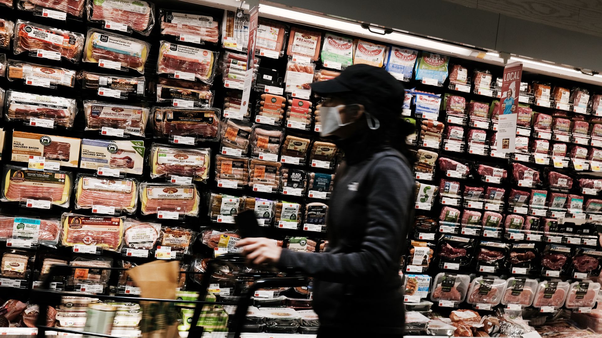 People shopping in the meat aisle in a grocery store 