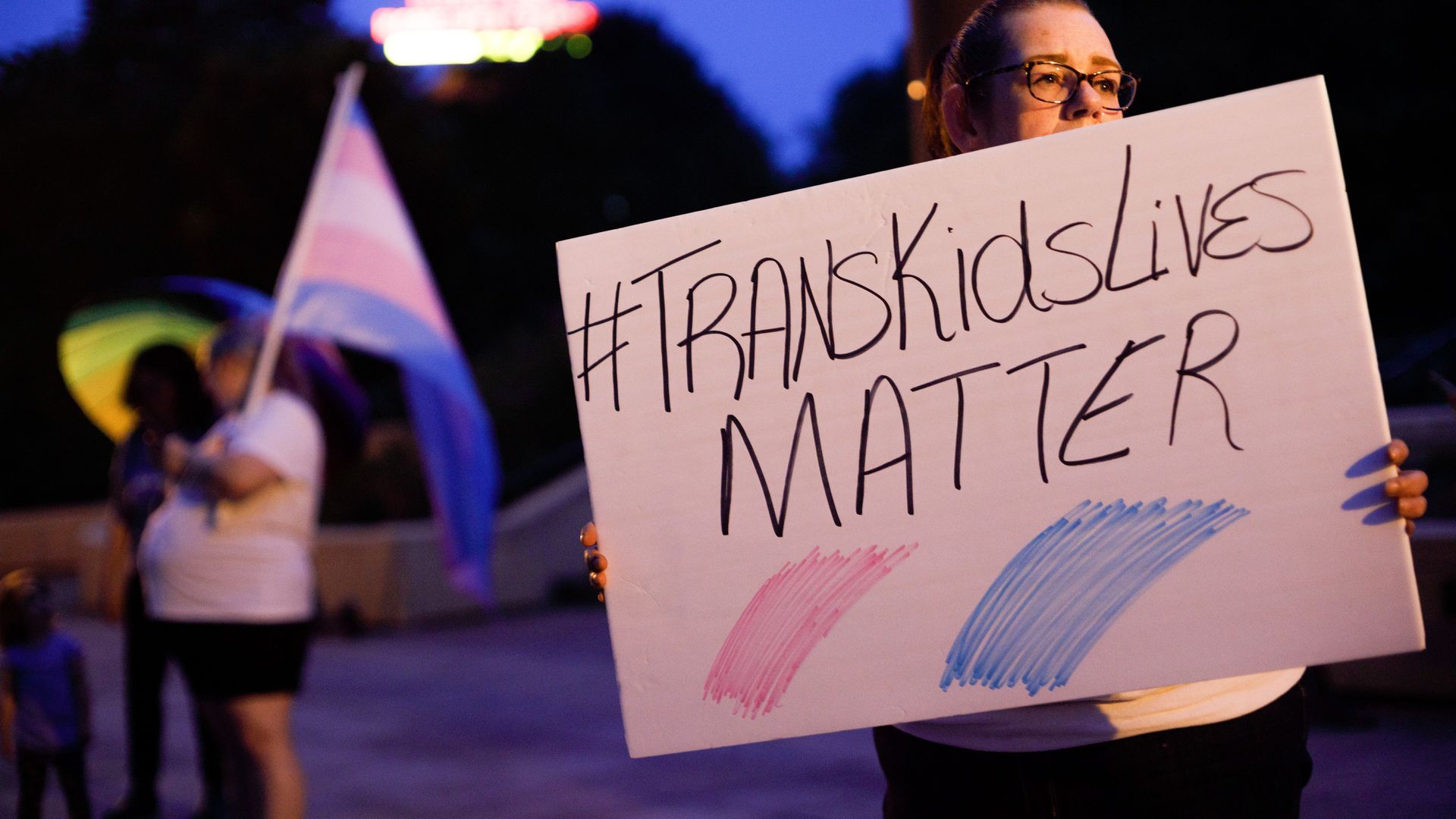 A person holds a sign reading #TransKidsLivesMatter