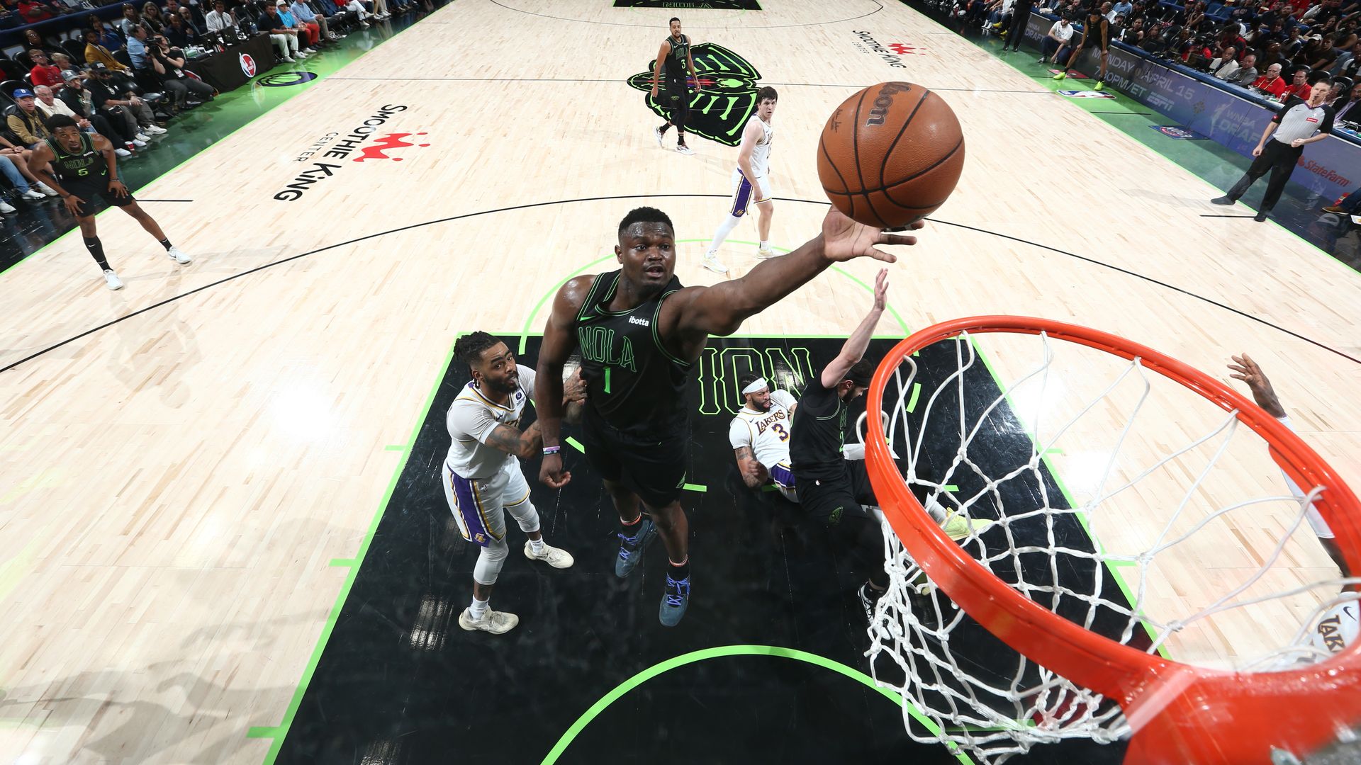 Zion Williamson reaches toward a basket with a basketball just coming off his fingertips.