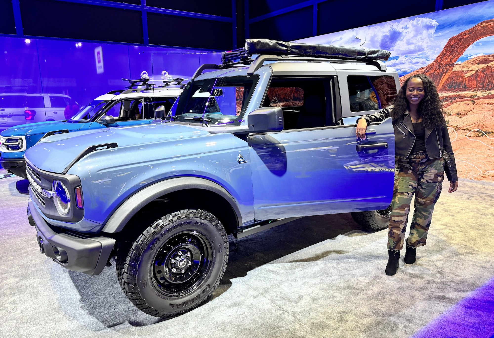 A blue truck with door open with Moyo leaning on the door and posing.