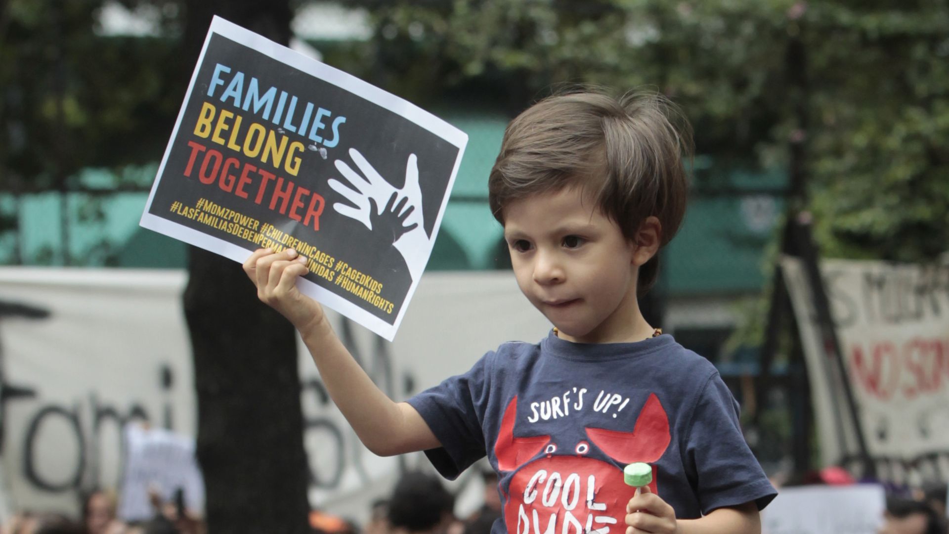 A child holds a sign that reads, "Families Belong Together," during a protest of family separation.