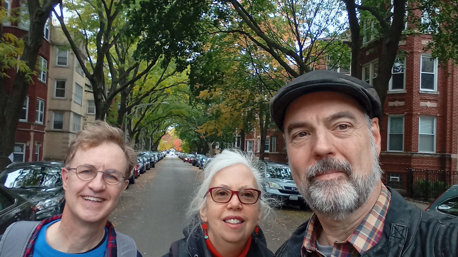 Three people in front of a treelined street