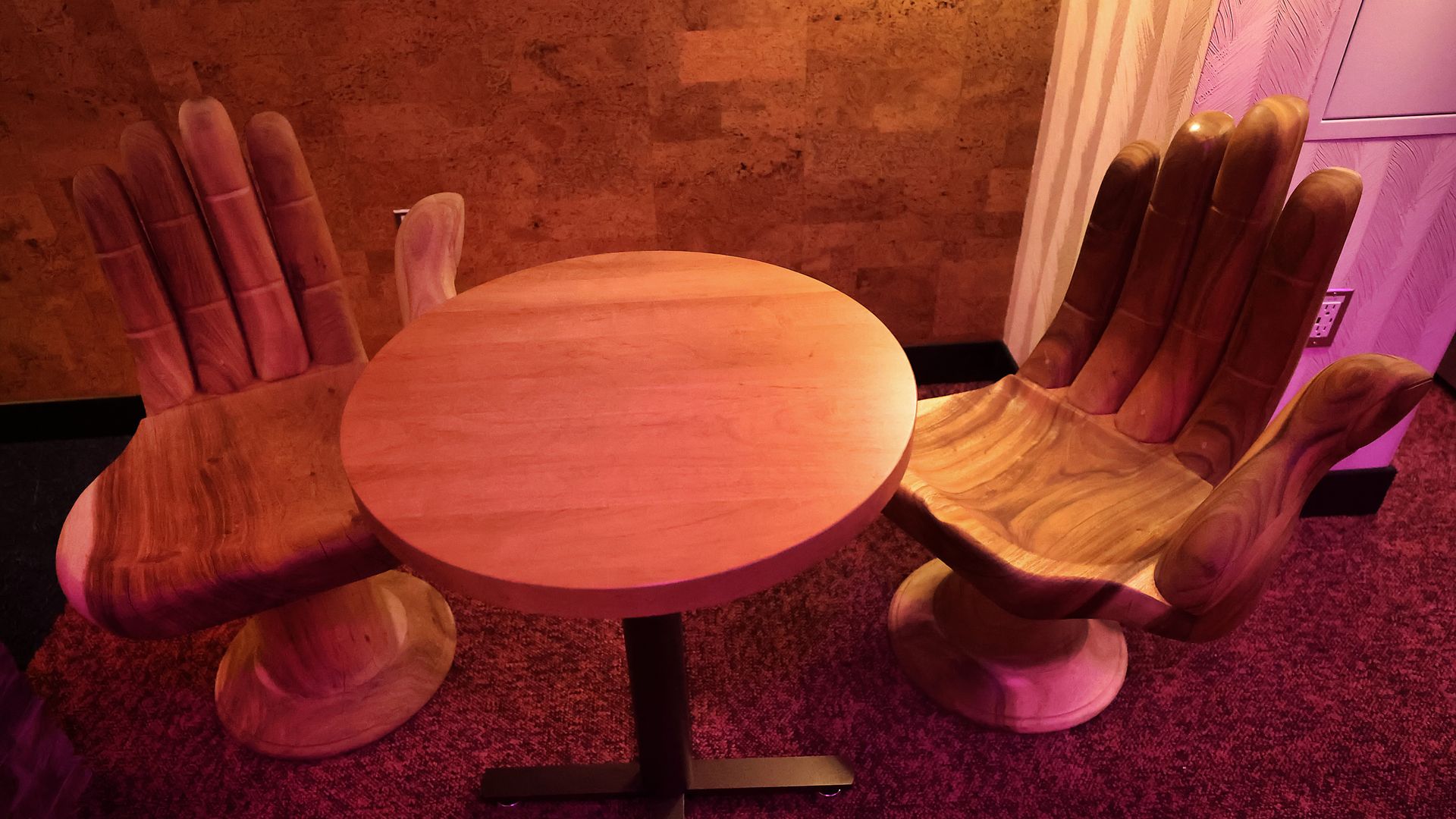 A round table with two wooden chairs shaped like hands inside Life Alive restaurant in Cambridge.