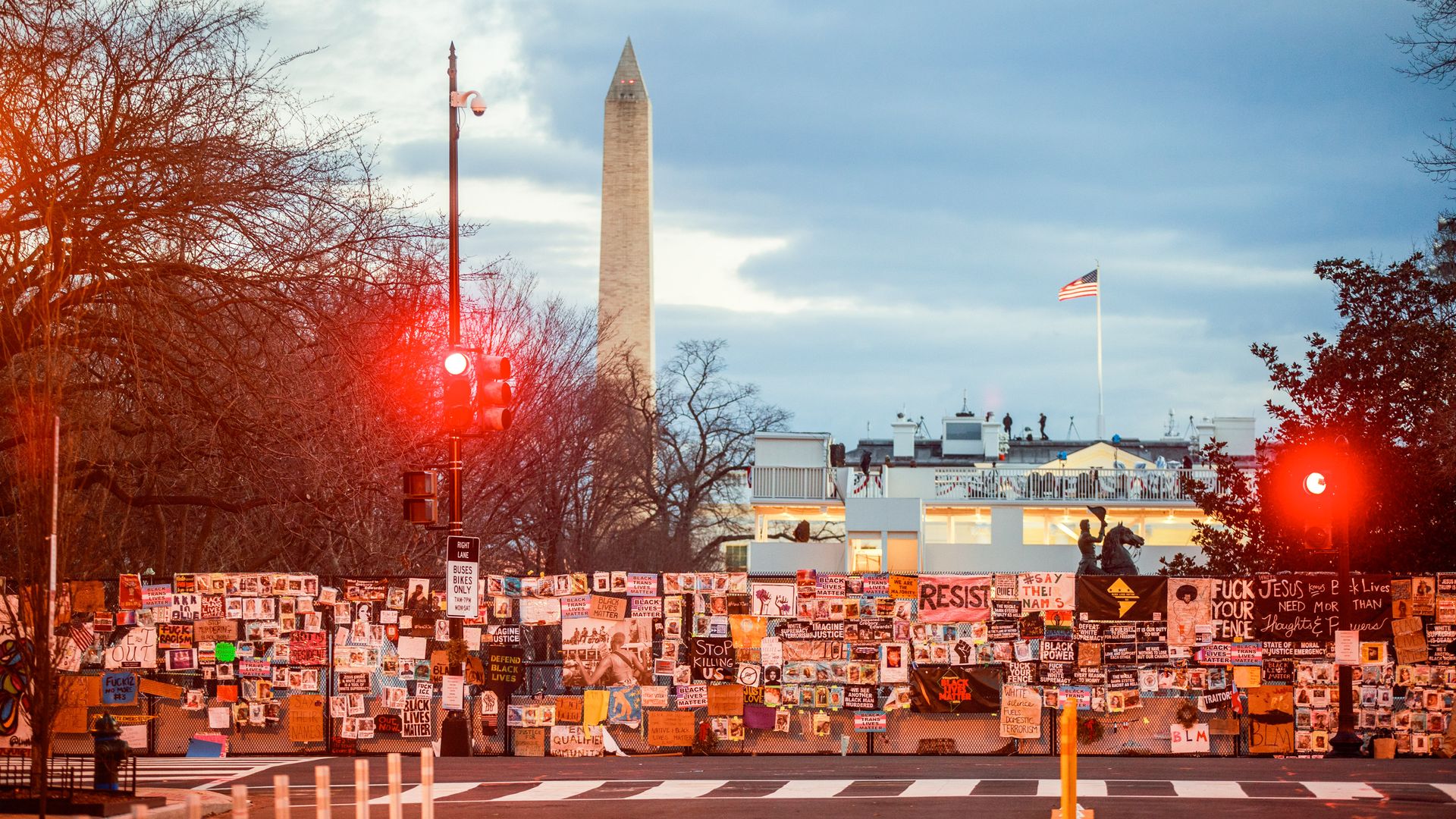 Photo of Black Lives Matter signs and art posted on a fence surrounding the White House; Washington Monument towers in the back