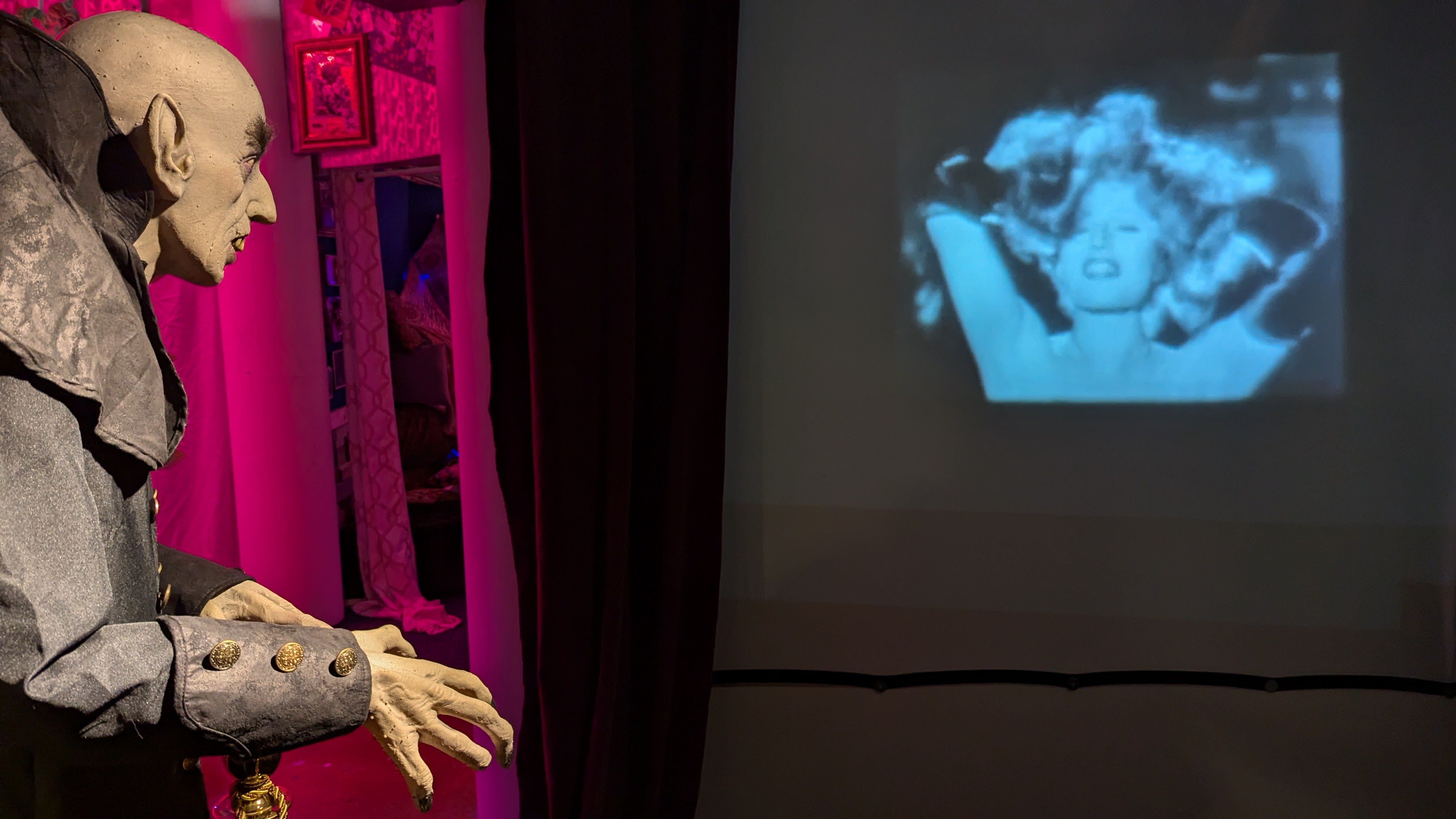A statue of nosferatu watches a film clip of rita hayworth tossing her hair. 