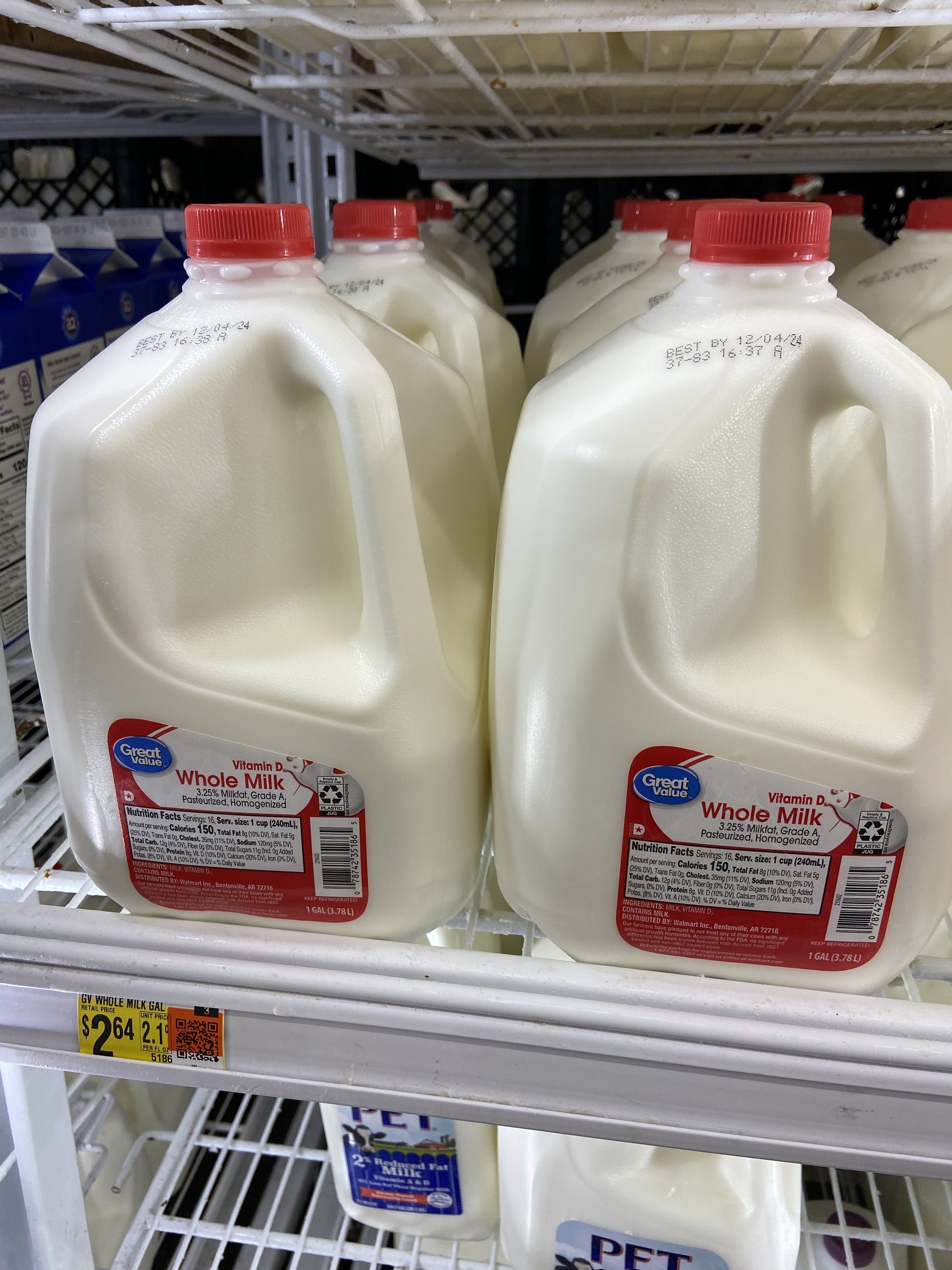 Gallons of whole milk on shelves at Walmart.