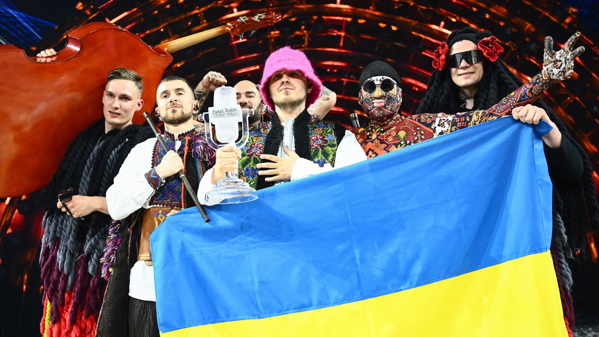 Members of the band "Kalush Orchestra" pose onstage with the winner's trophy and Ukraine's flags 