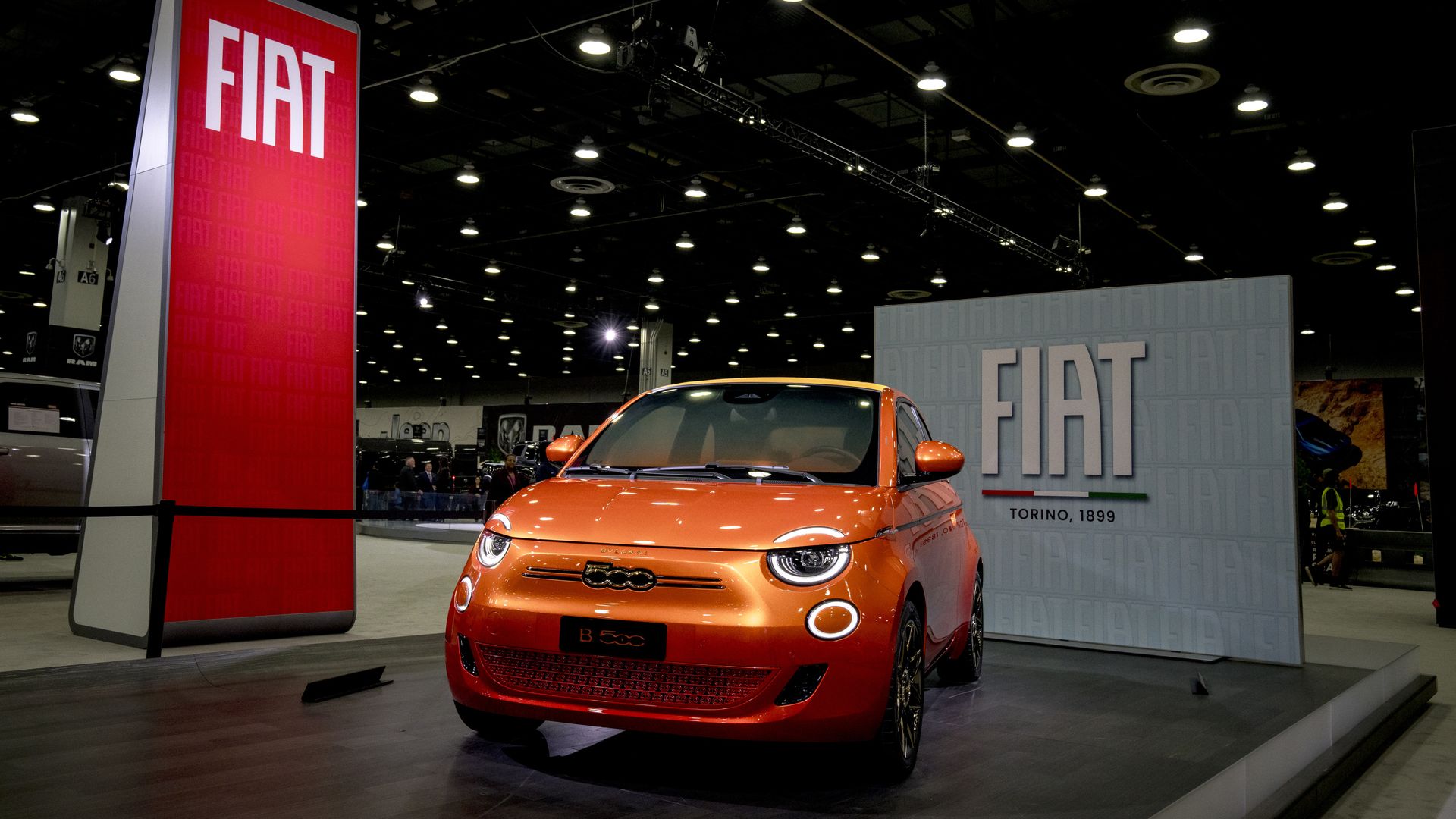 A tiny orange car at an auto show