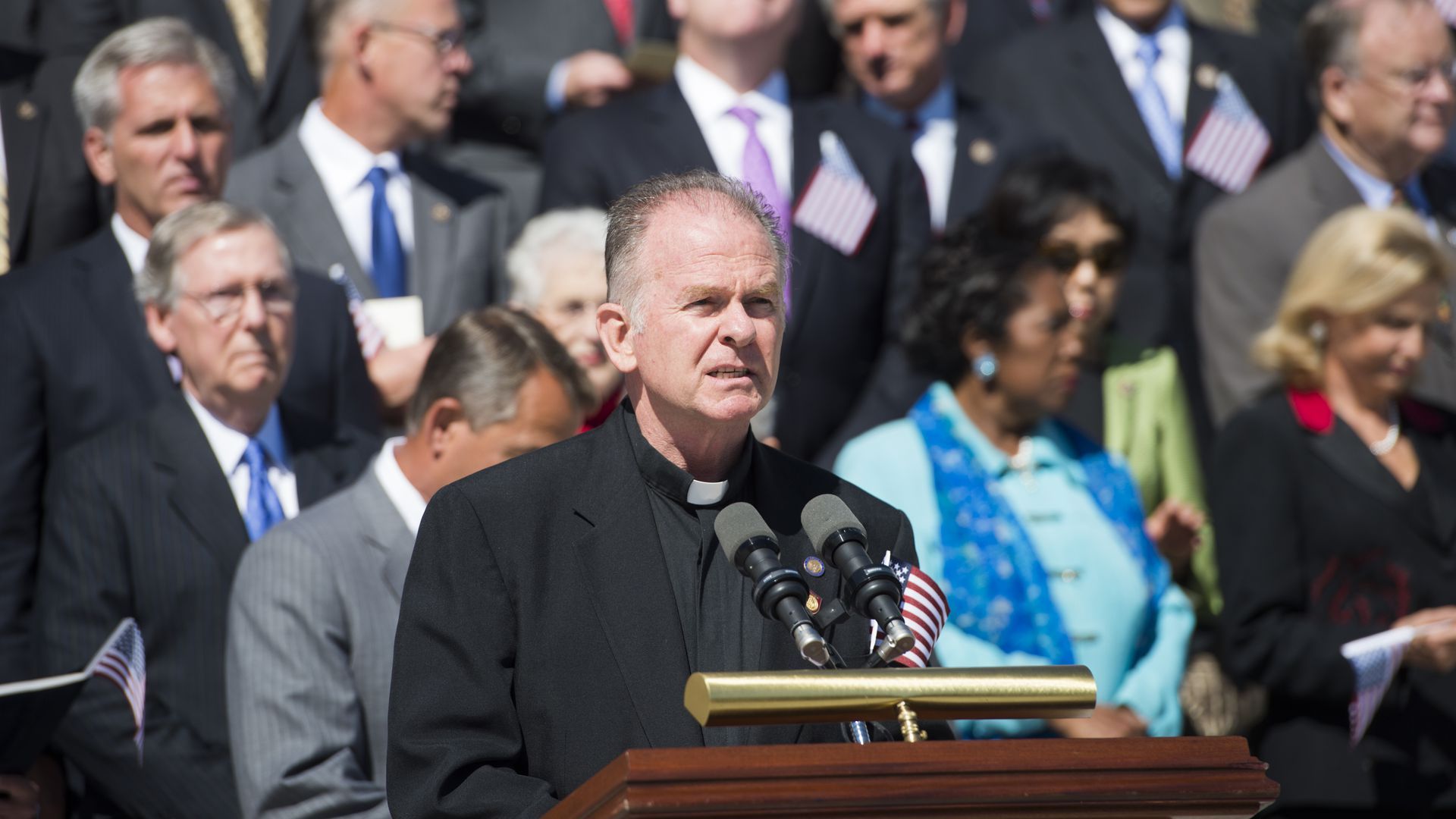 Reverend Patrick J. Conroy, Chaplain of the U.S. House of Representatives, speaks to a crowd from a podium