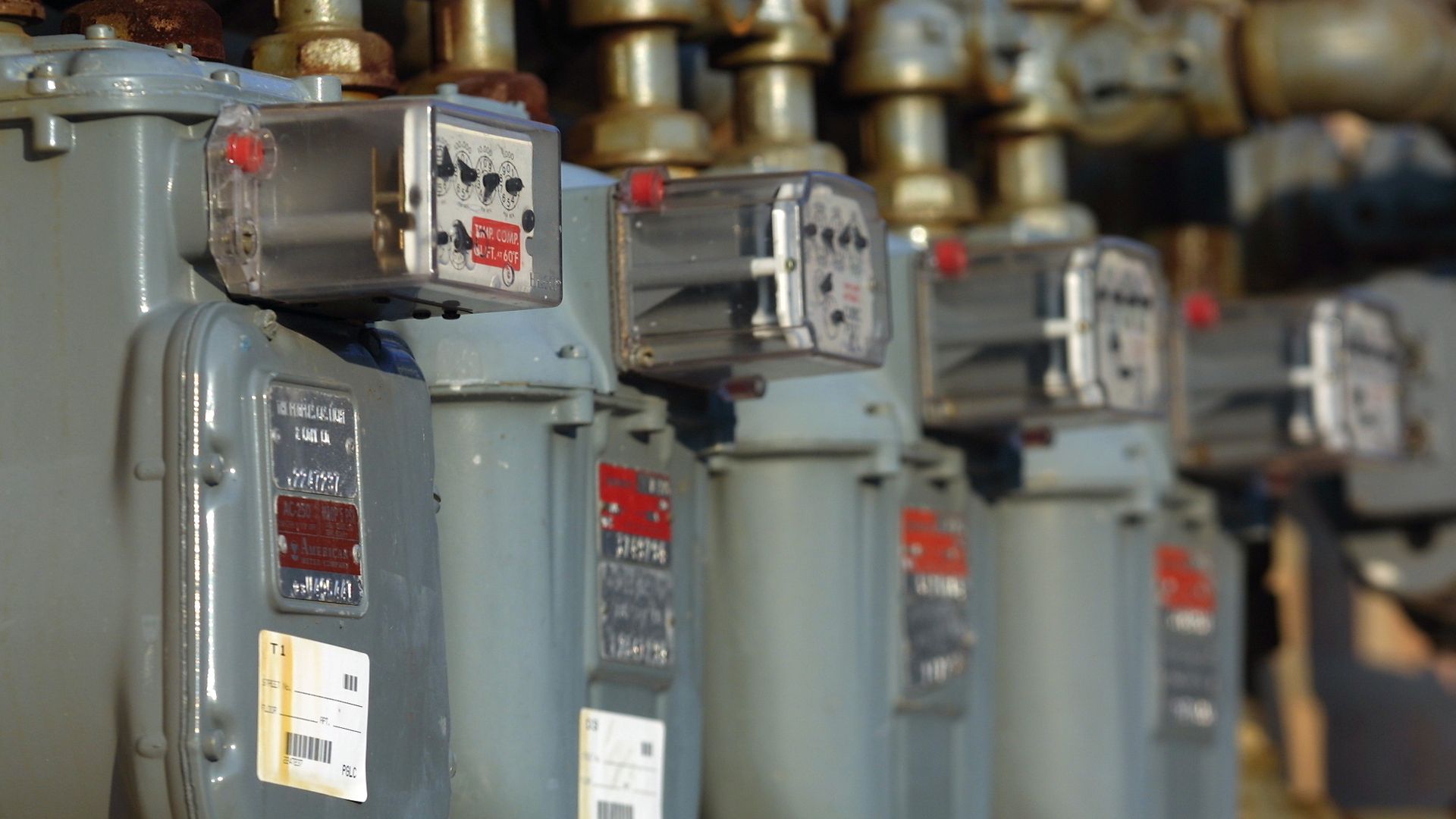 Several natural gas meters hang near a wall of a commercial building.
