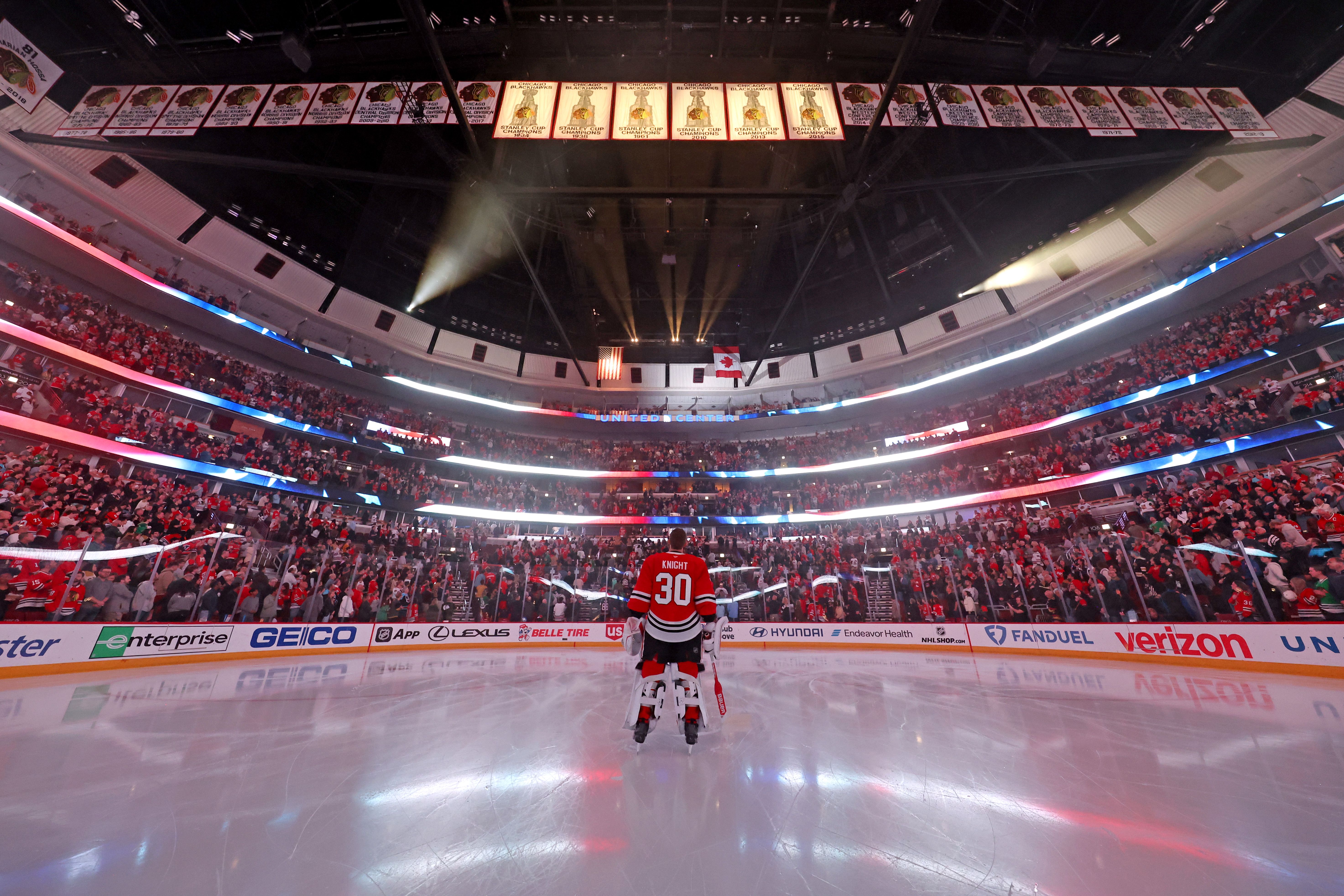 Photo of a hockey player standing in the middle of the ice surrounded by screaming fans at a stadium. 