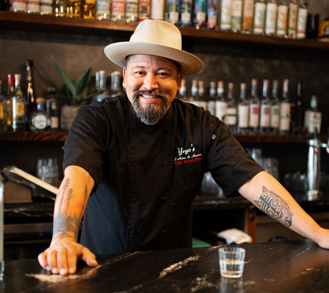 man standing behind a bar with smile