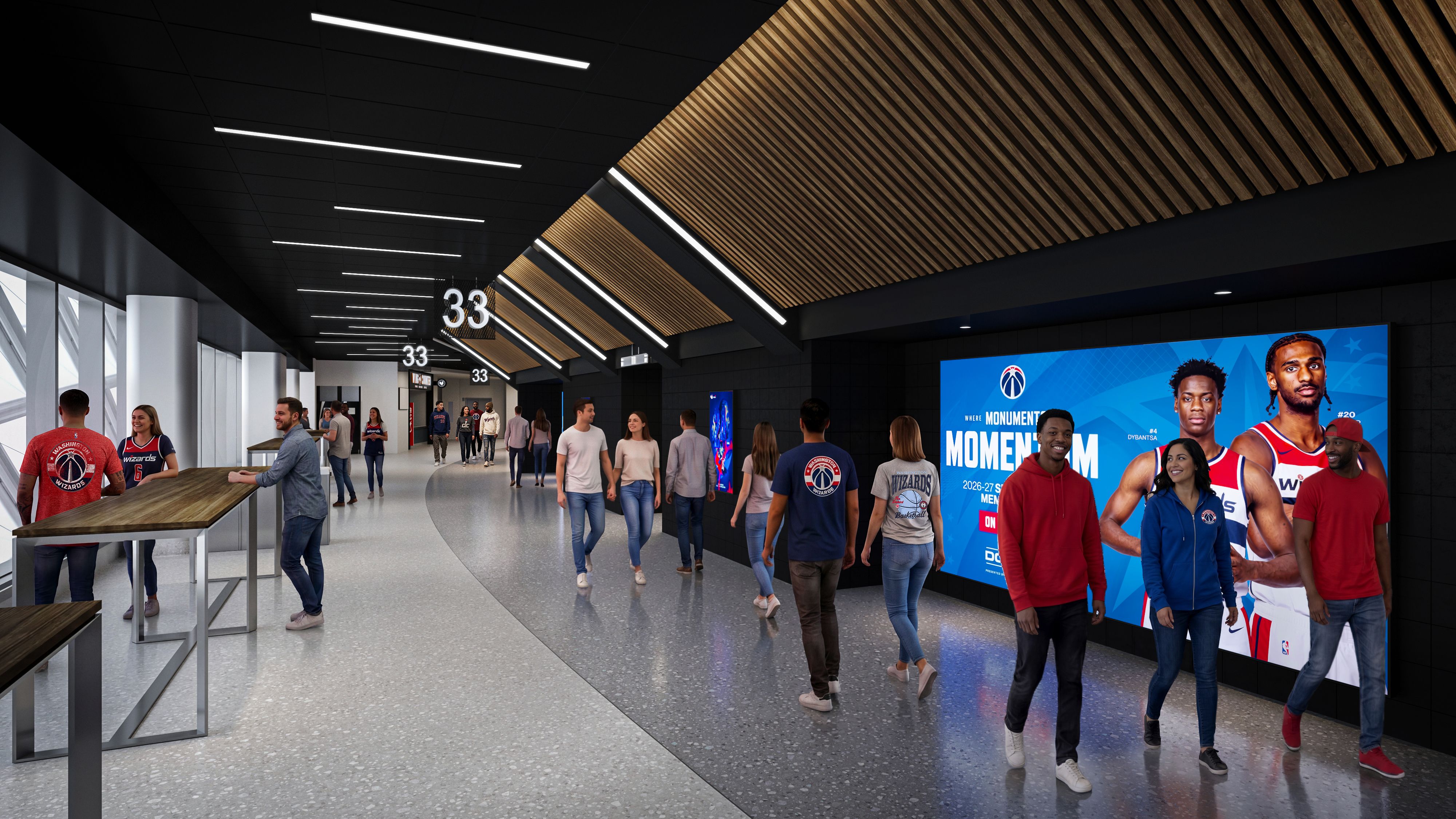 Indoor stadium concourse with a dark ceiling and white linear lights, wood slat panels on the right, and a large blue basketball promo screen. People walk, many wearing Wizards gear.