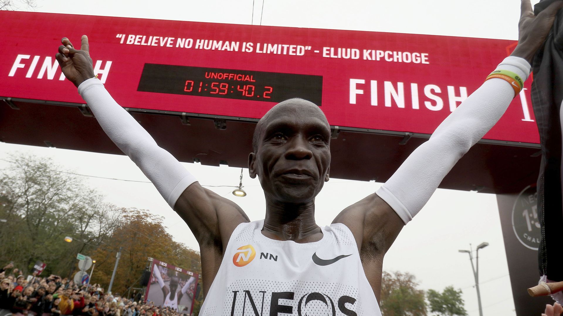 In this image, Kipchoge raises his arms in victory just past the finish line, which displays his unofficial finish time and a quote from him that reads "I believe no human is limited"