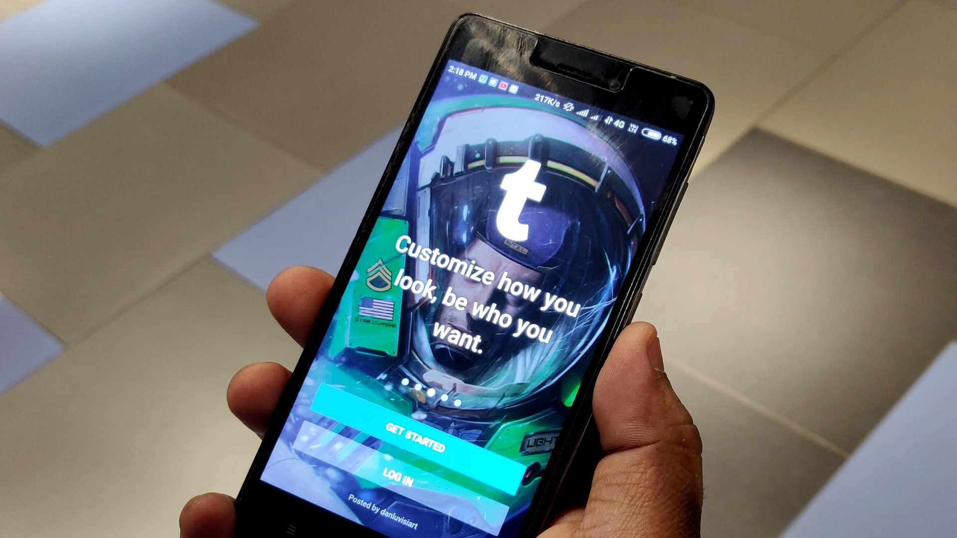 In this image, someone holds a phone with the Tumblr login screen displayed. The text on the screen reads: Customize how you look, be who you want.