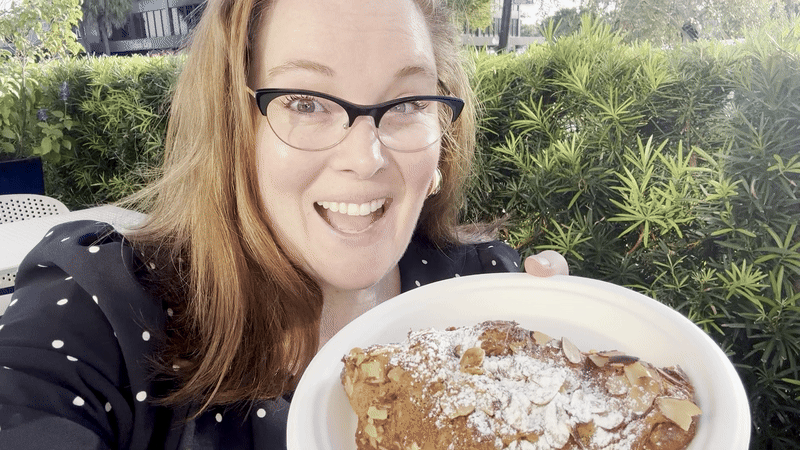 Image shows Carlie smiling with an almond croissant.